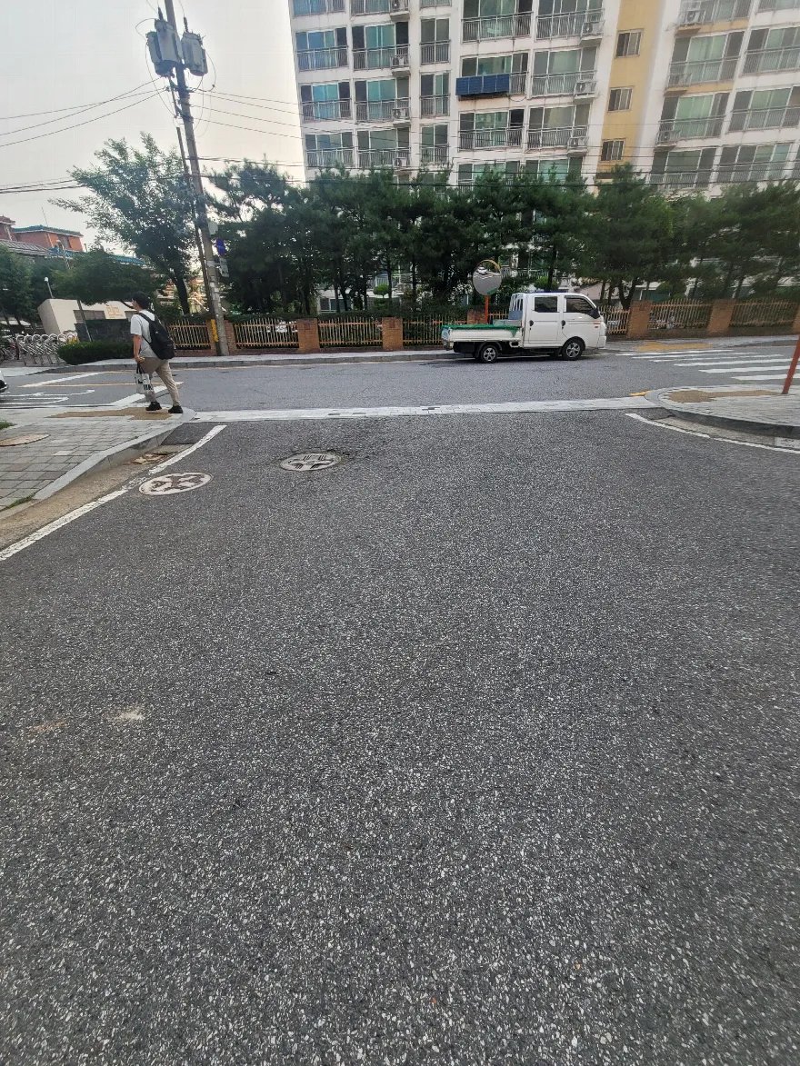 단지로 들어오는 진입 도로 포장을 끝낸 상태로, 노면 전체가 고르게 깔려 있습니다.
