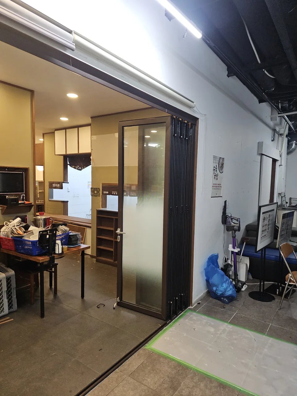 상업공간 출입구에 짙은 갈색 프레임의 폴딩도어(접이식 도어)가 설치된 모습임.
