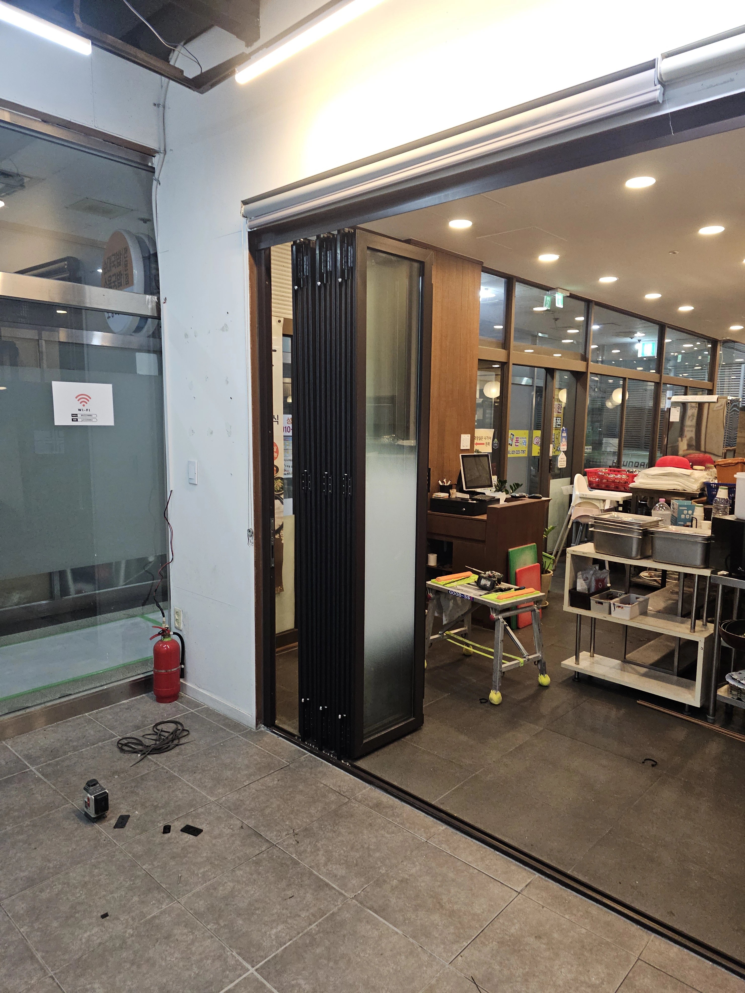상가로 보이는 공간의 출입구에 폴딩도어(주름식 중문)가 설치되어 있는 모습입니다.