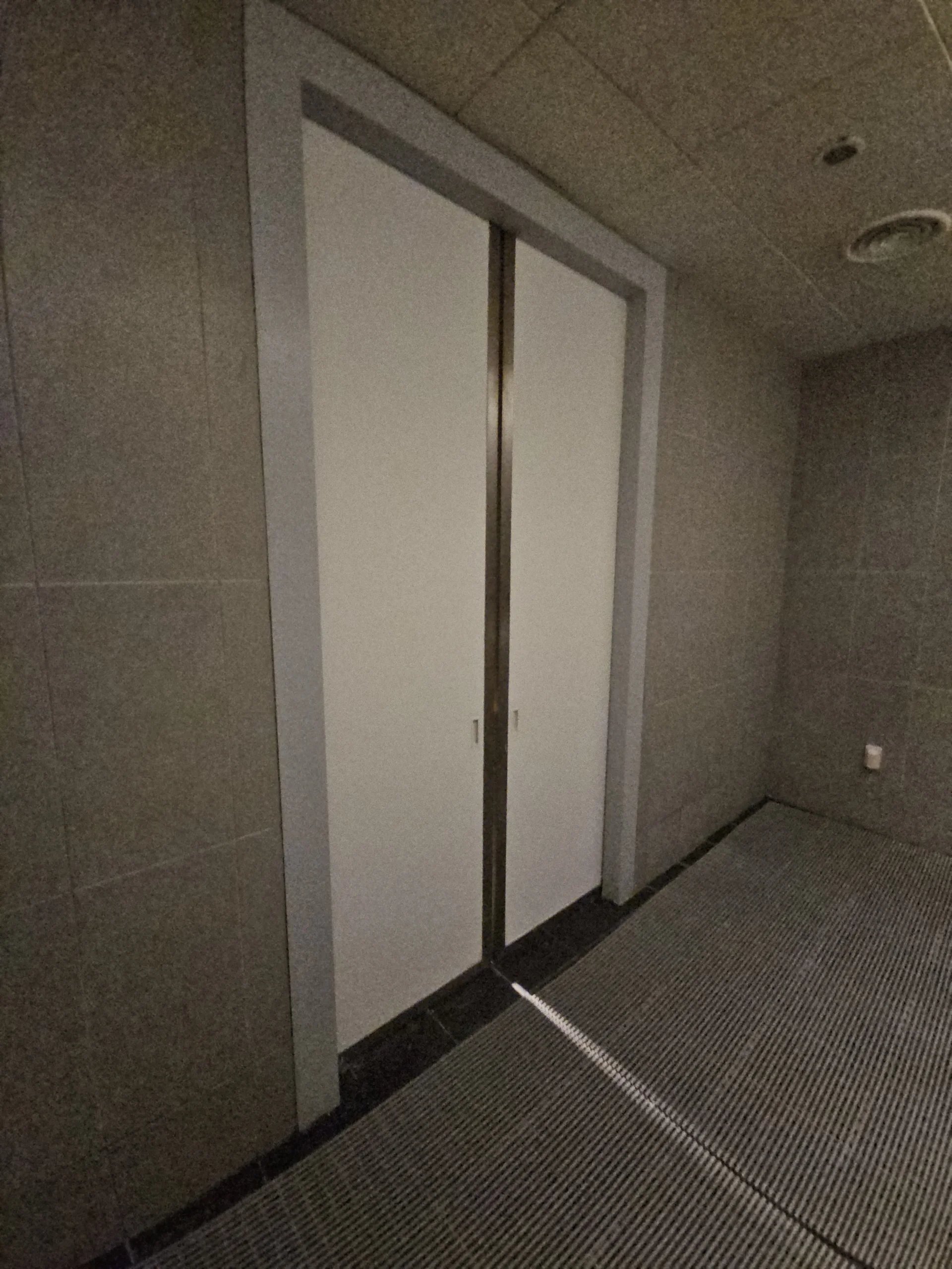 타일로 마감된 공간 안쪽에 흰색 2연 미닫이문이 설치된 모습입니다.