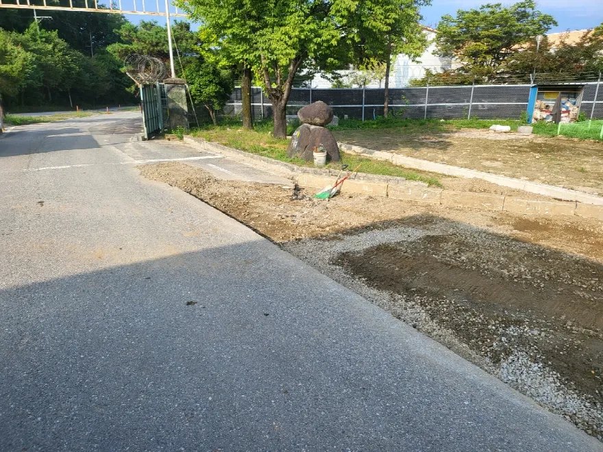 도로와 맞닿은 부지 경계 쪽으로 관로 작업을 마치고 흙을 되메워 지표를 고르게 정리한 상태로 보입니다.