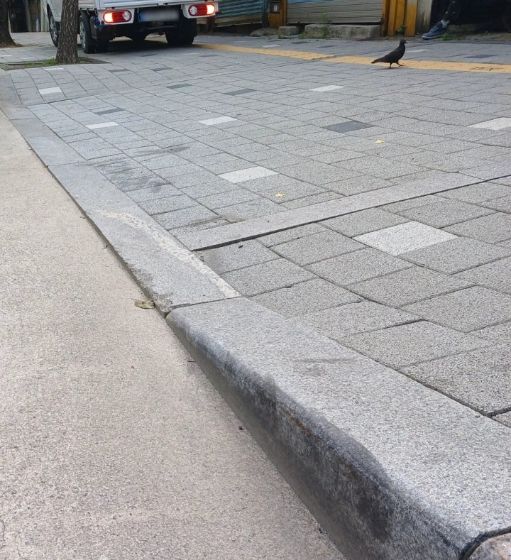 보도블록과 화강석 경계석이 맞닿는 구간을 가까이서 찍은 사진으로 경계석이 새로 시공되어 단차가 정리되어 있다.