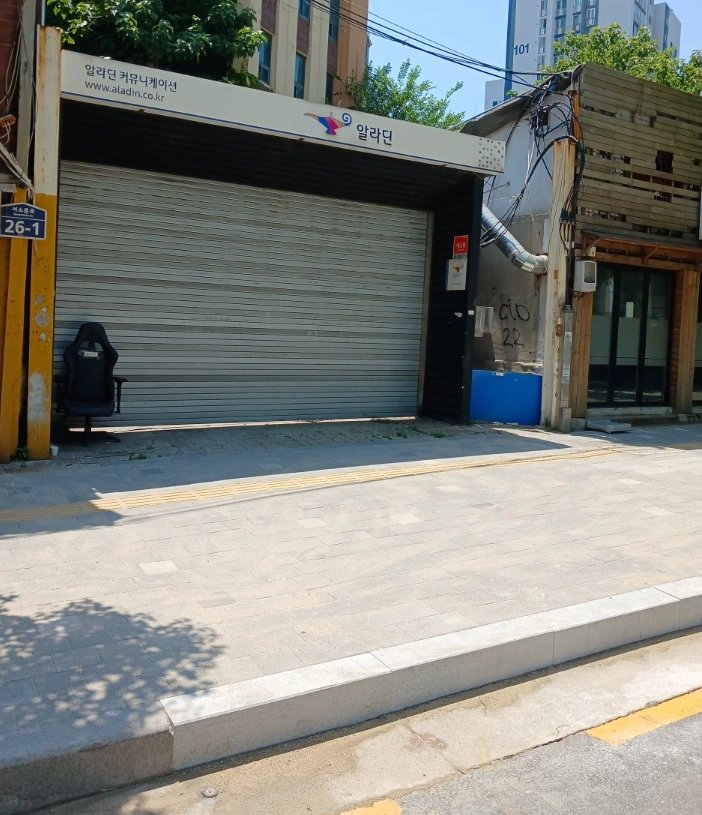 상가 셔터 앞 도로가 밝은 색 보도블록으로 새로 포장되어 있고 도로 경계를 따라 화강석 경계석이 가지런히 시공되어 있다.