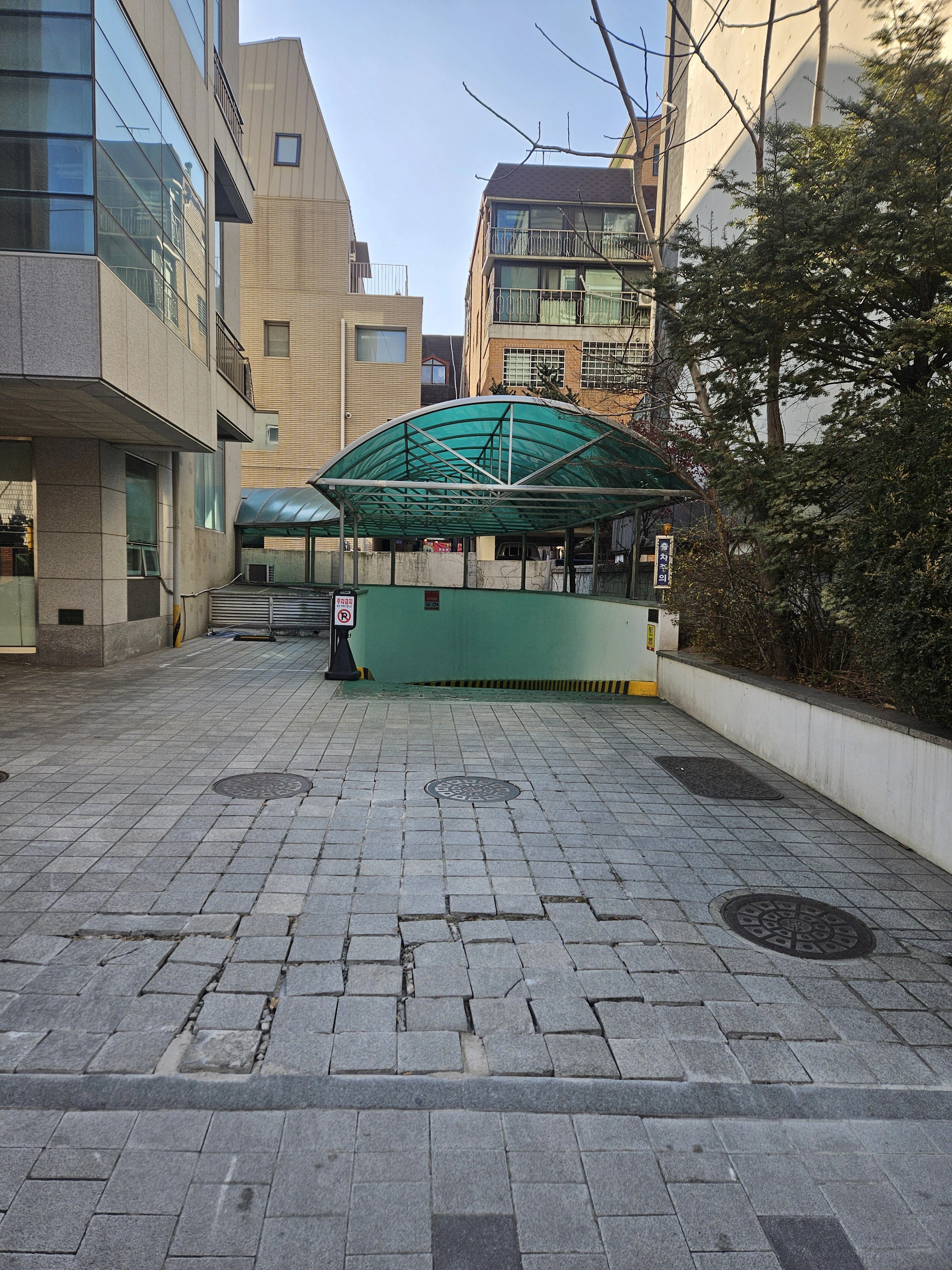 건물 사이 진입 통로 바닥에 사각 블록 형태의 포장재가 시공되어 있는 모습입니다.