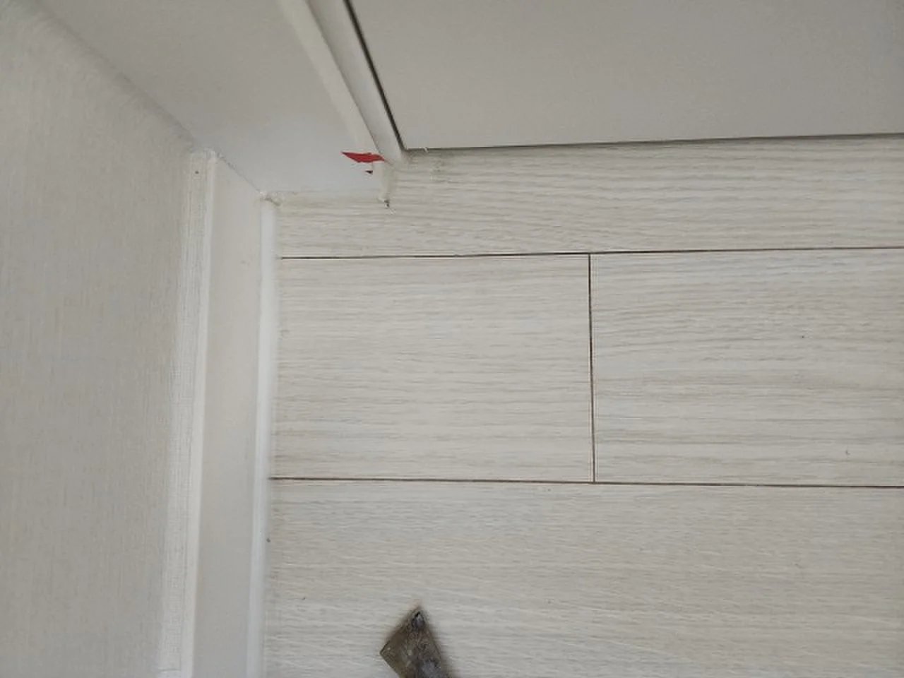 우드톤 무늬목 패널이 시공된 벽면 상단과 천장 몰딩이 맞닿는 구간을 올려다본 각도의 사진.