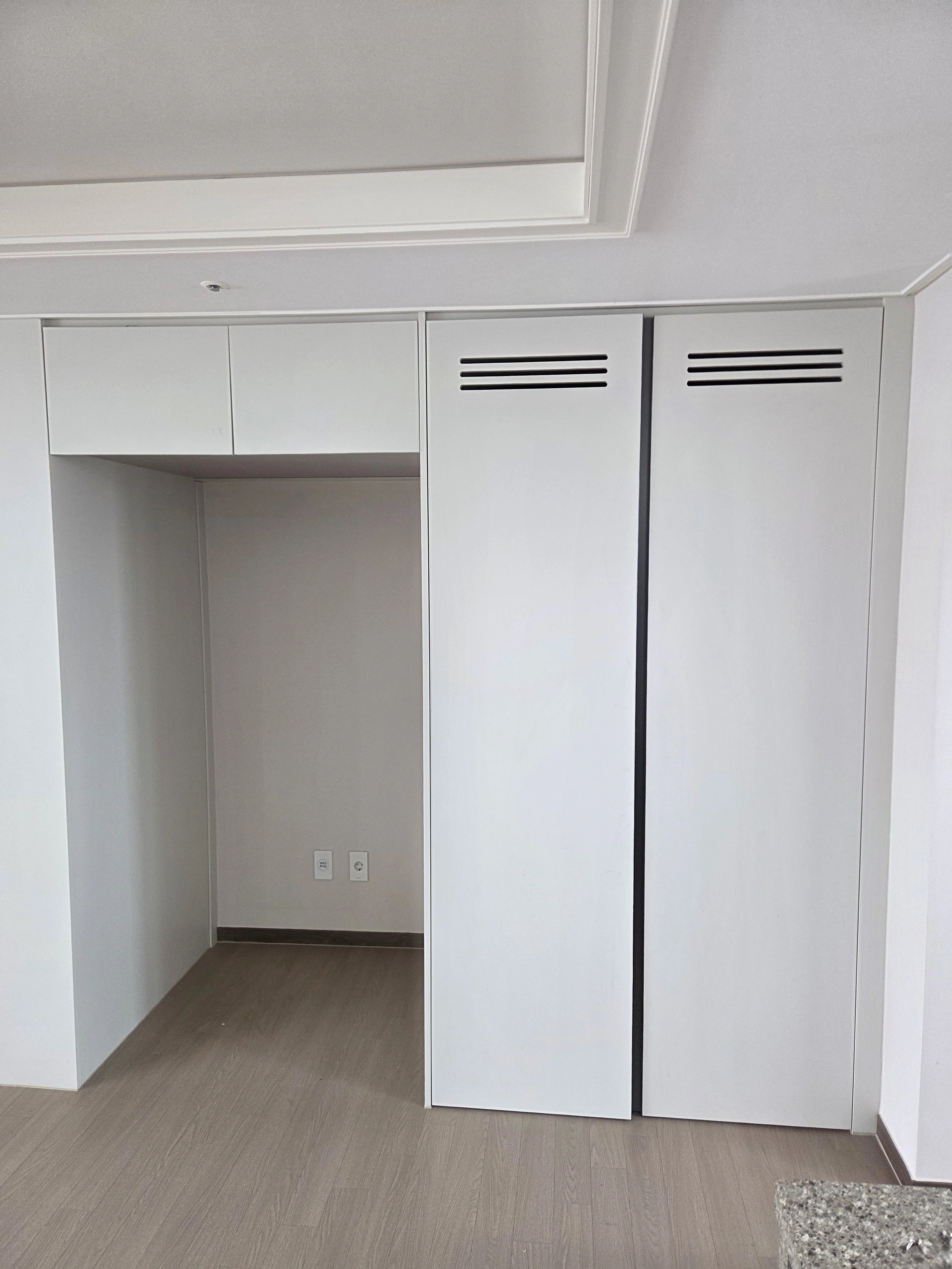 냉장고가 들어갈 공간을 비워두고 상부장과 측면 수납장을 흰색으로 제작·설치한 모습이다.
