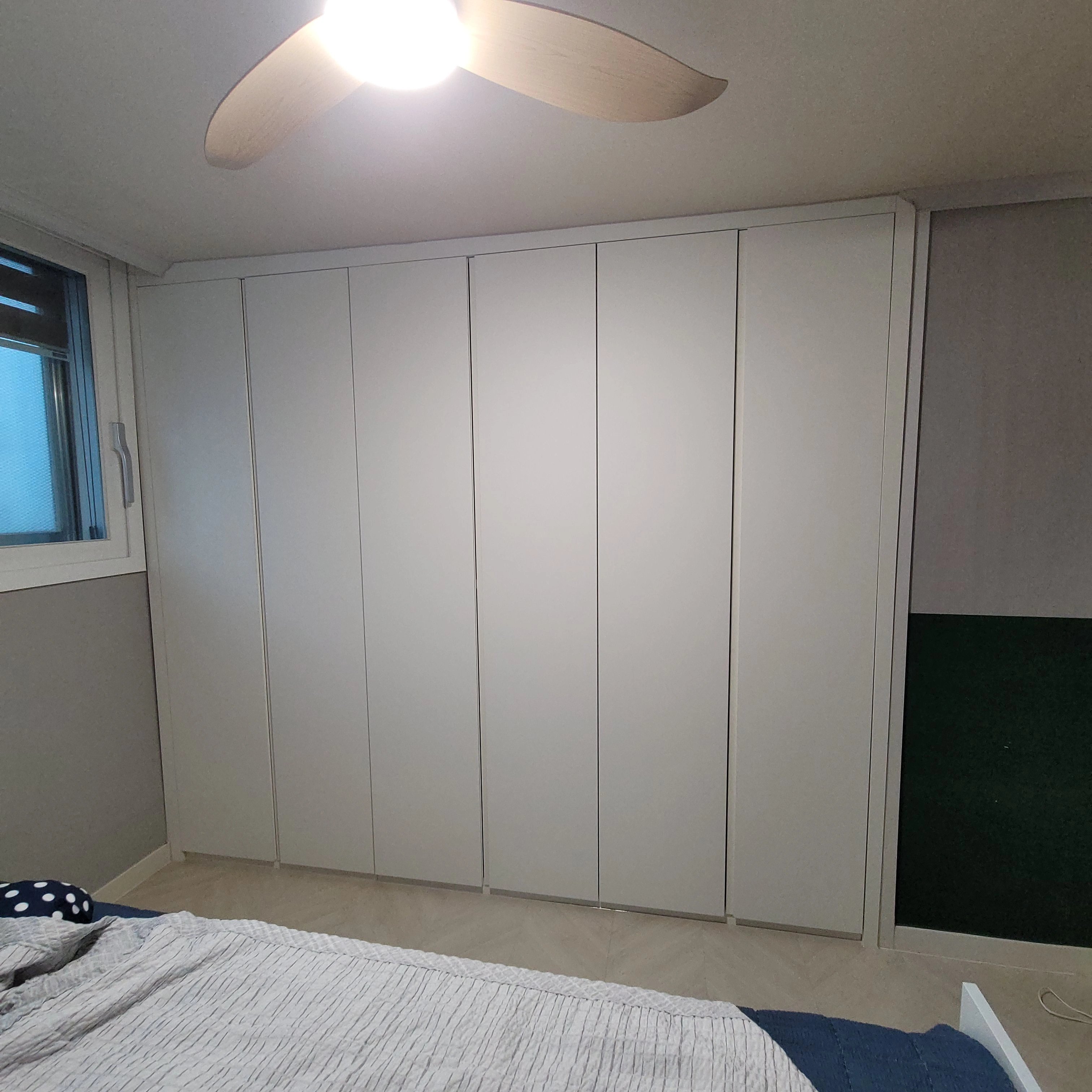 침실 한쪽 벽을 가득 채운 화이트 붙박이장 완료 사진입니다.