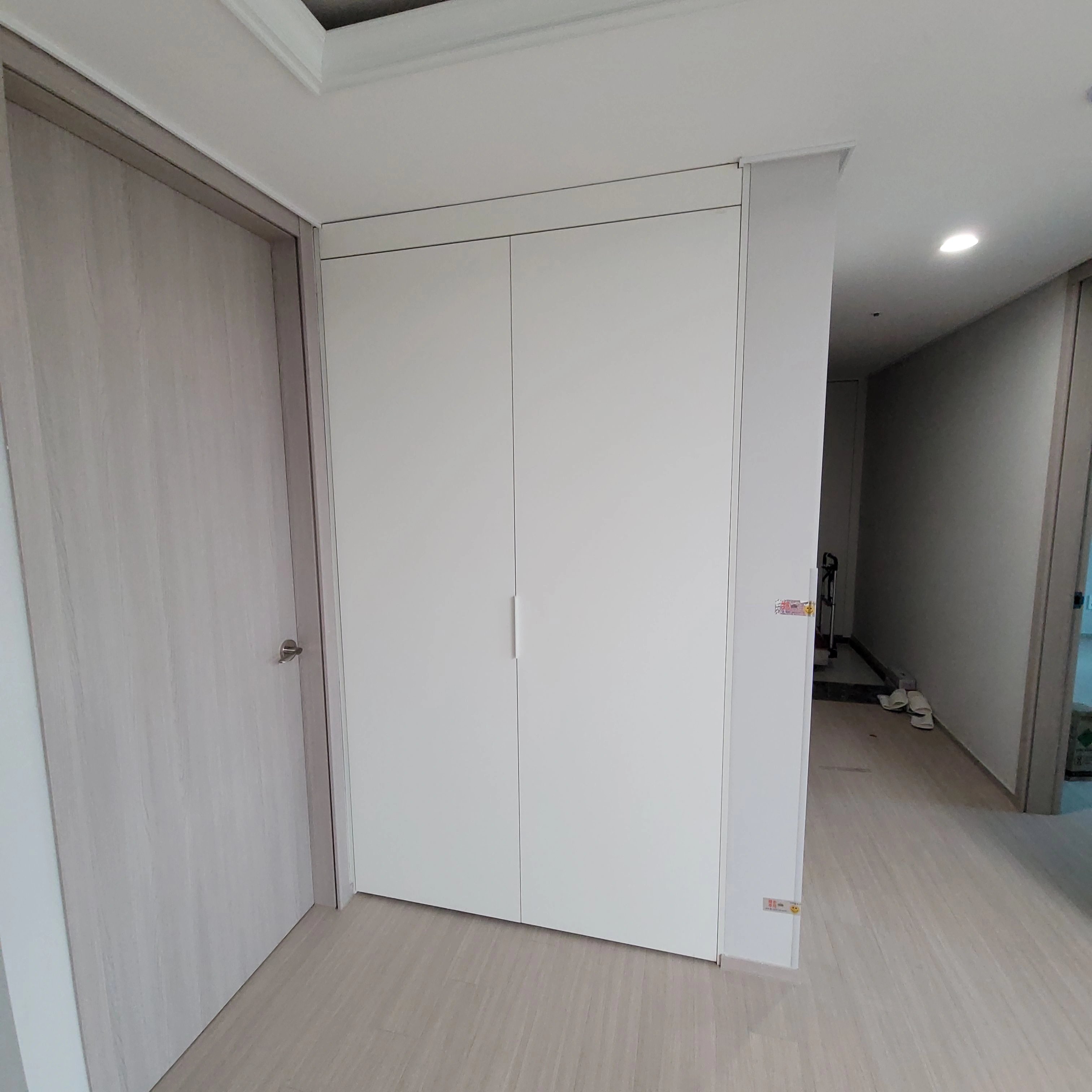 복도 한쪽 벽면에 맞춰 짜 넣은 흰색 붙박이장 시공이 마무리된 모습입니다.