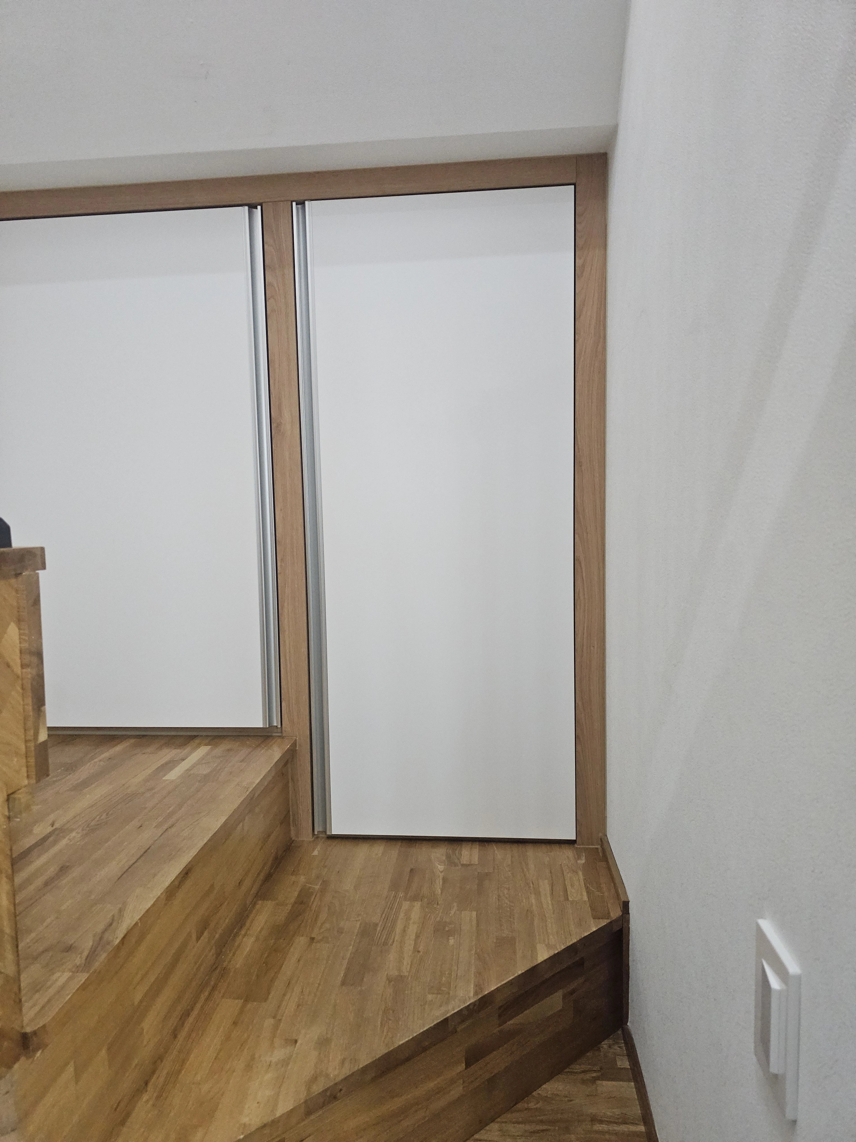 계단 옆 다락 공간에 원목 무늬 프레임의 슬라이딩 도어 붙박이장을 제작·설치했습니다.
