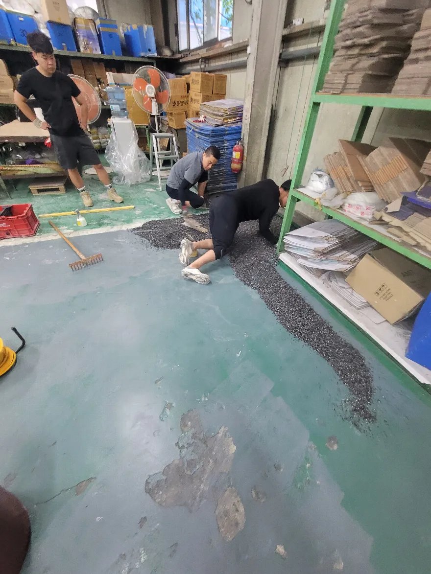 배합한 검은 콩자갈을 바닥에 부어 벽면 선반 쪽 라인부터 펴 나가고 있습니다.