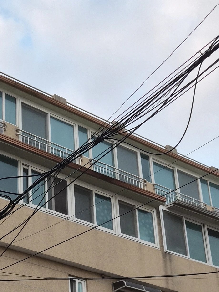 건물 외벽을 올려다본 사진으로, 창문과 발코니 난간이 층마다 반복되는 구조가 보인다.