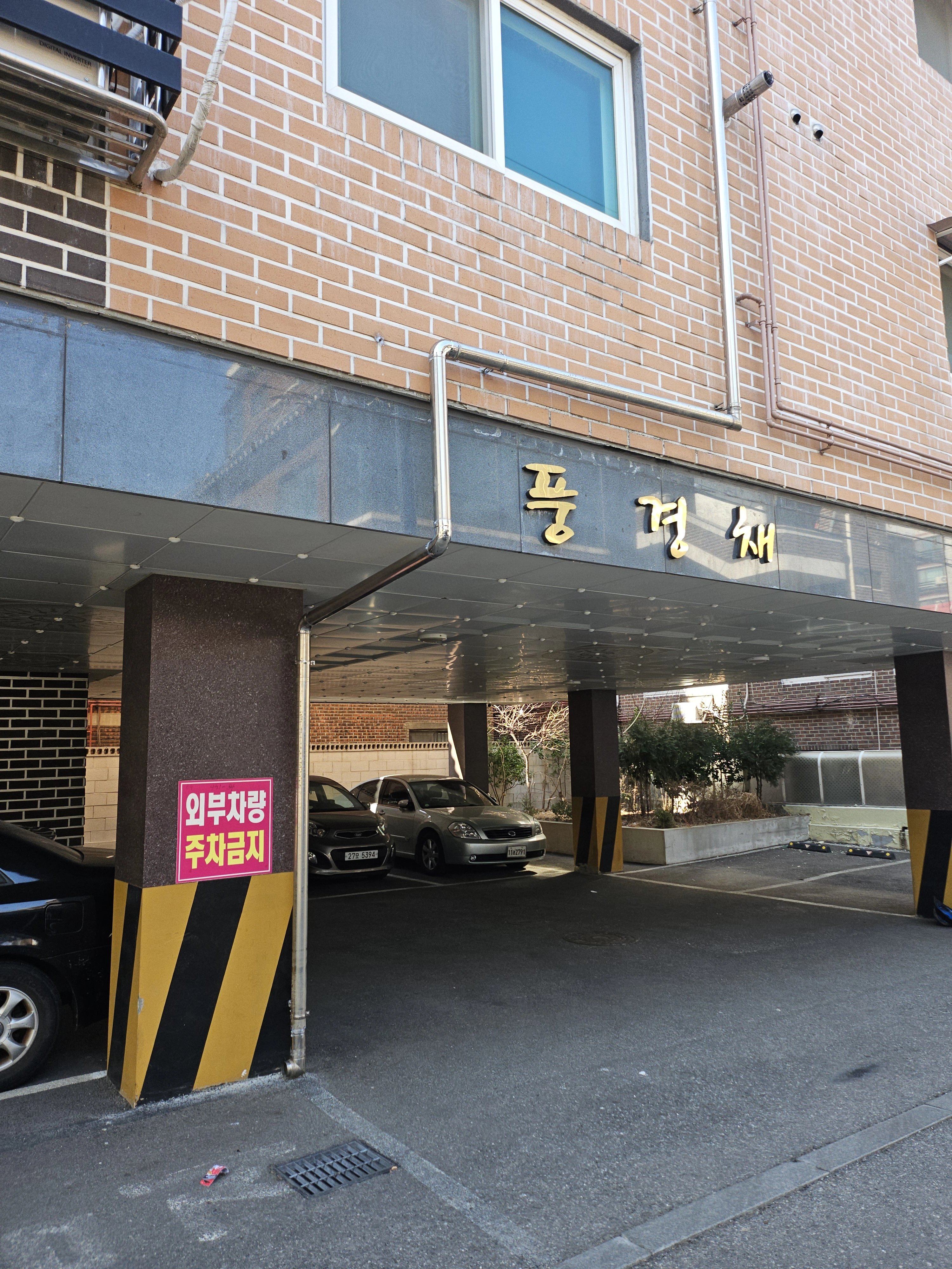 벽돌로 마감된 건물 외벽을 따라 흰색 우수관이 수직으로 설치되어 있다.
