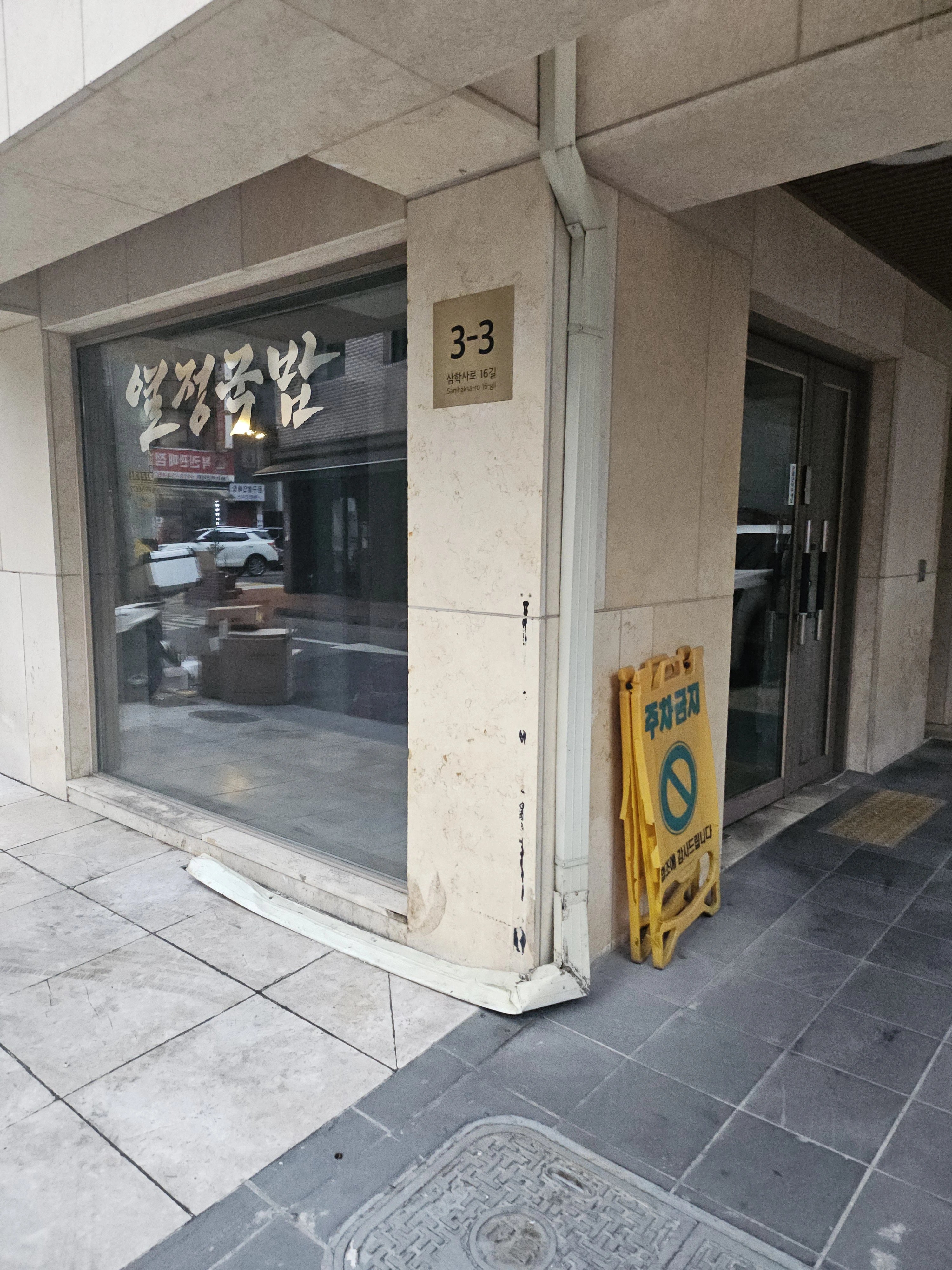 상가 건물 모서리 기둥을 따라 내려오는 우수관 하단부를 촬영한 사진으로 보임.