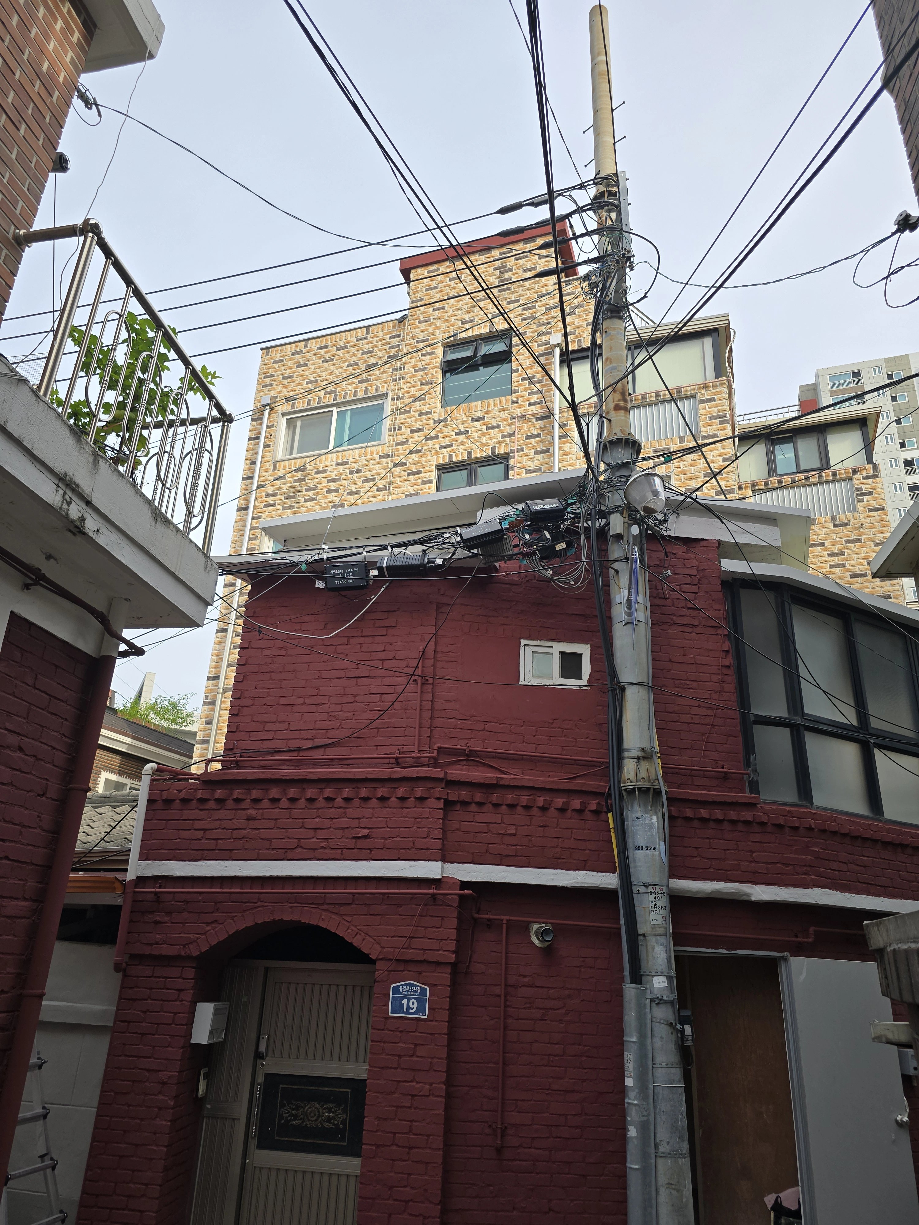 붉은 벽돌 건물 외벽을 따라 설치된 배관이 건물 우측 모서리 쪽에 보입니다.