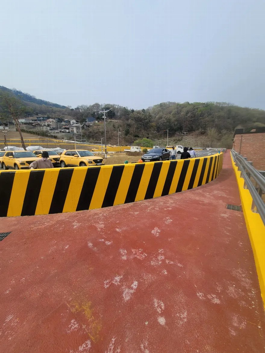 옹벽 벽면 전체에 노랑·검정 사선 도색이 들어간 완료 상태입니다.