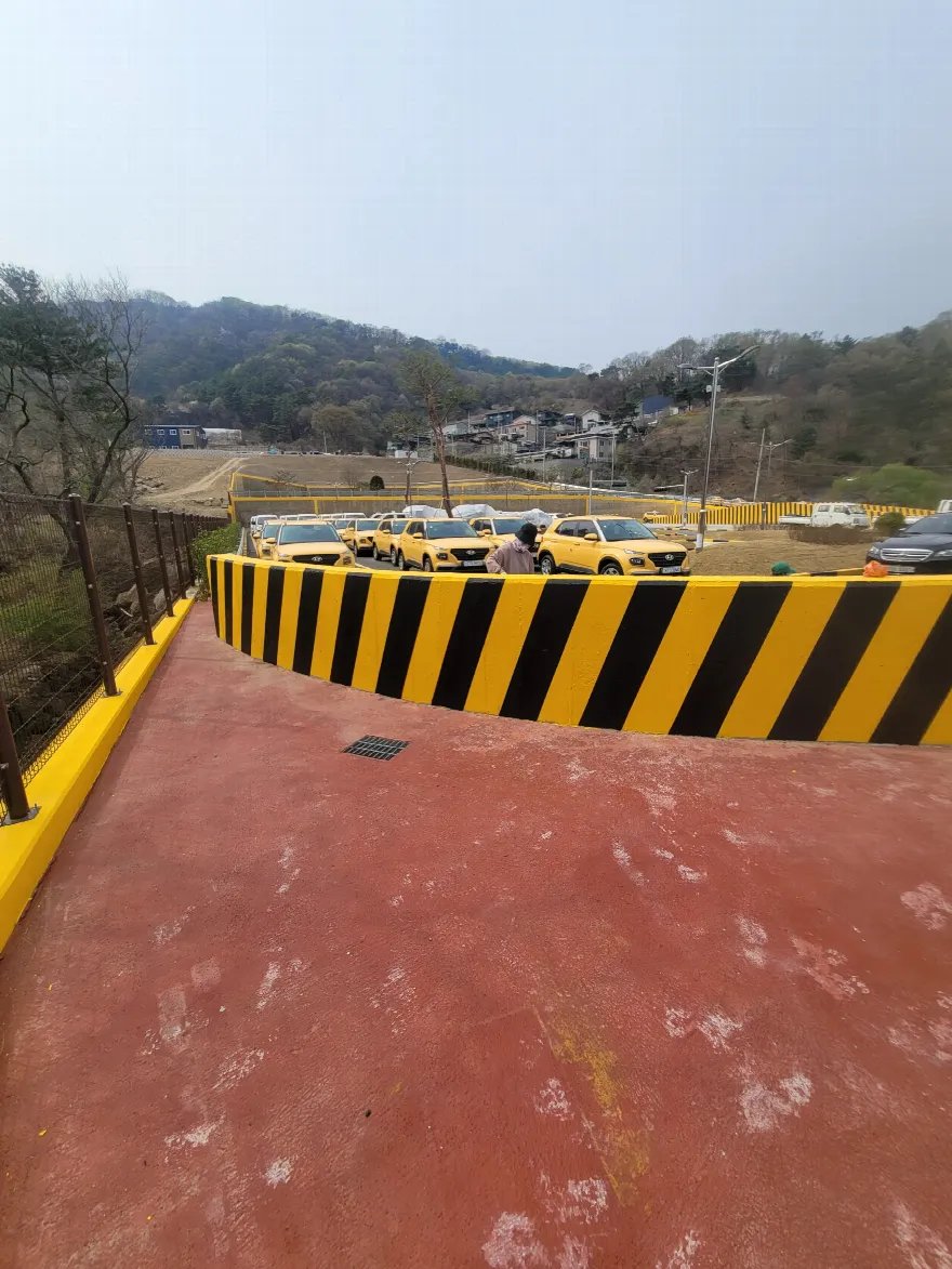 같은 옹벽 구간을 조금 더 가까이에서 본 완료 사진으로, 사선 도색된 벽체가 곡선을 그리며 시야를 가로지릅니다.