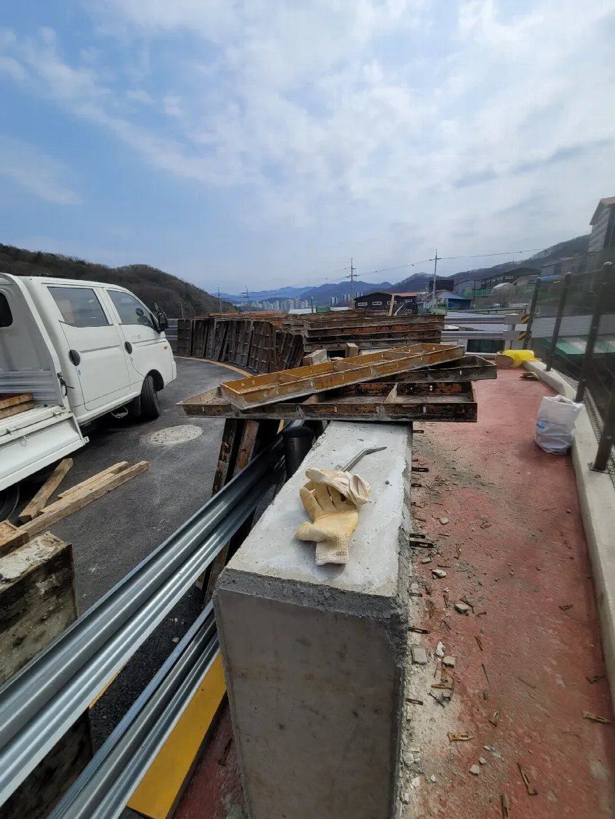 타설이 끝난 콘크리트 벽체 상단 위로 자재를 걸쳐 두고 다음 구간을 준비하는 모습입니다.