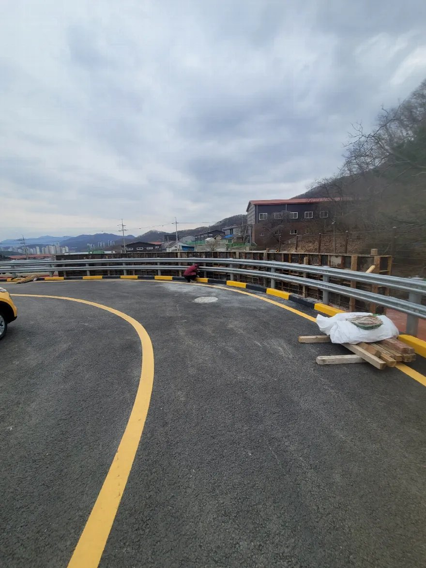 옹벽과 가드레일 시공이 끝난 도로 곡선 구간을 넓게 담았습니다.