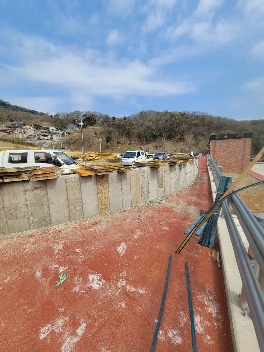 탈형이 끝난 콘크리트 옹벽이 길게 이어진 전경입니다.