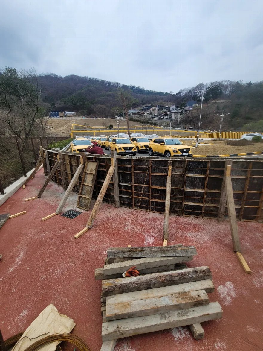 옹벽 벽체 거푸집을 세우고 지지대를 보강하는 작업 장면입니다.