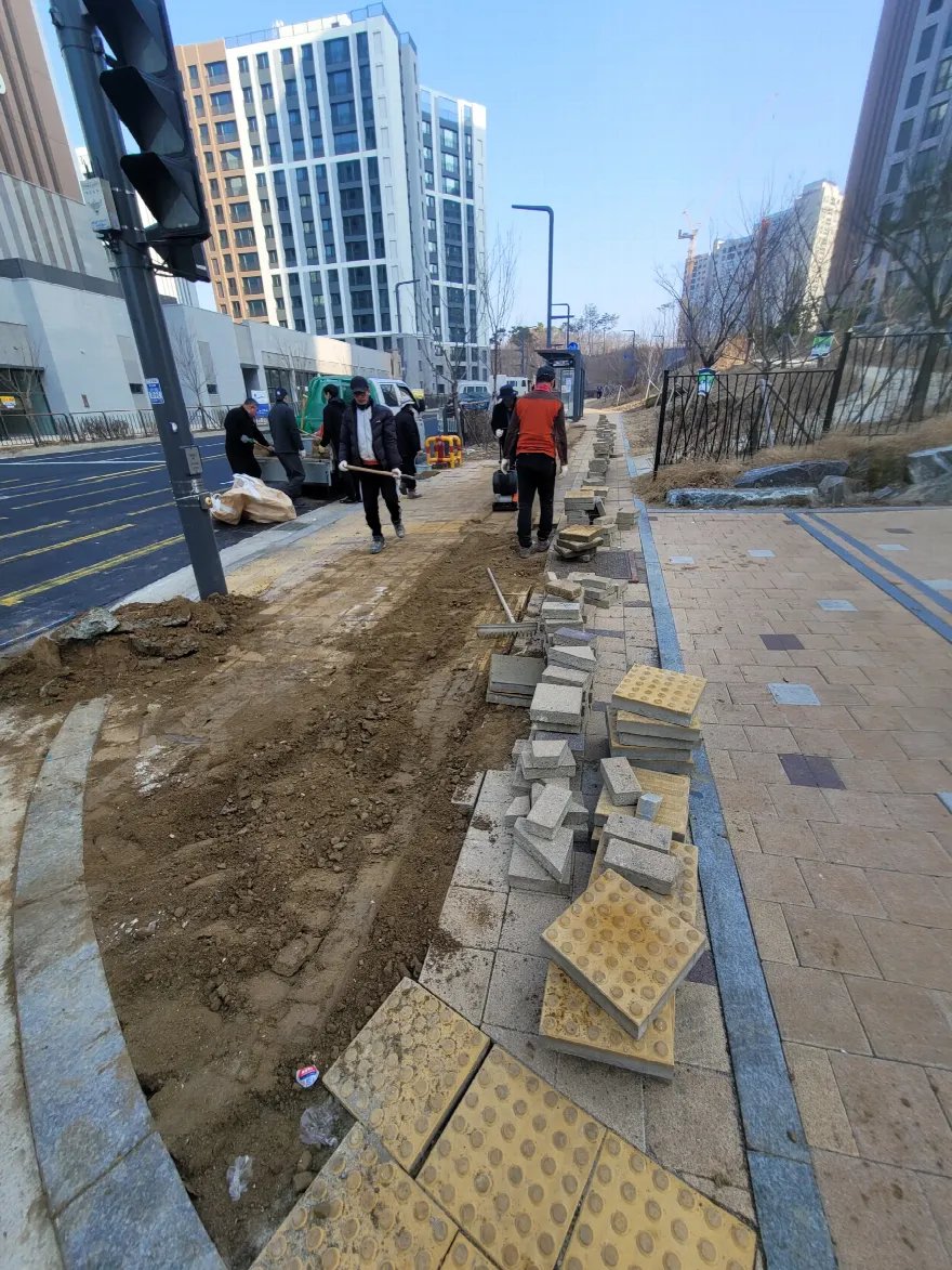 차도 옆 보도의 블록을 걷어내고 흙 기층을 드러낸 철거 단계입니다.
