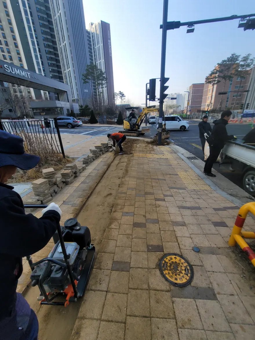 상가 앞 인도에서 블록을 걷어내고 기층을 다지는 작업 중입니다.