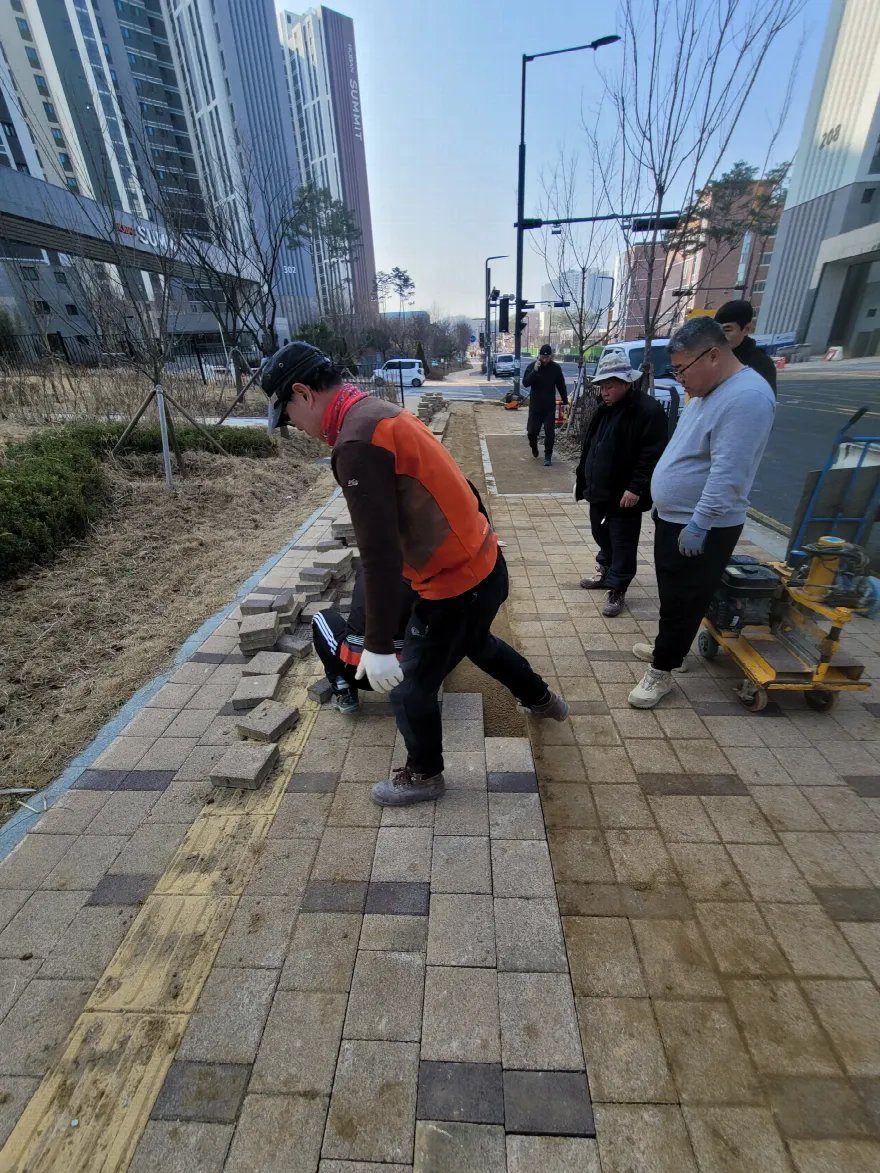 블록을 걷어낸 자리에 새 모래를 깔고 블록을 다시 놓는 시공 중 장면입니다.