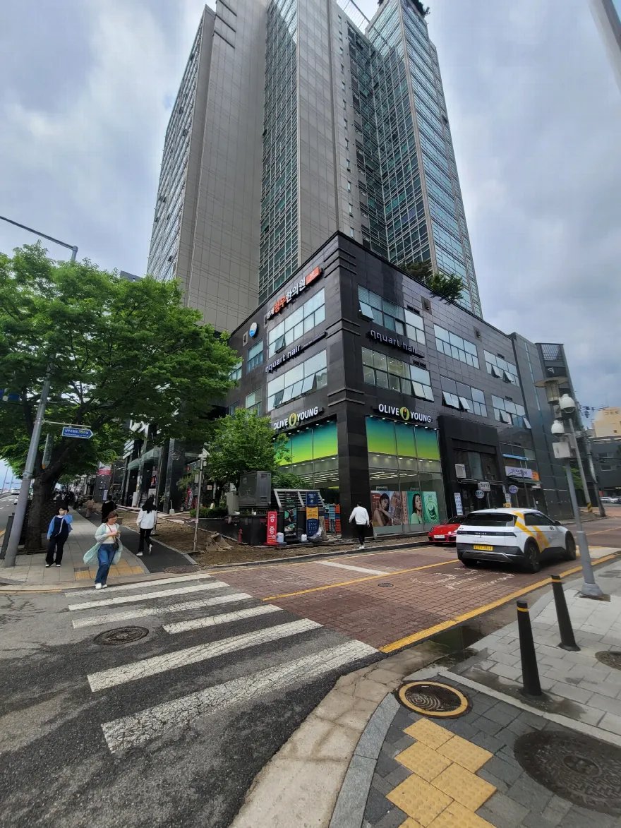 고층 건물 앞 교차로와 횡단보도를 넓게 찍은 사진입니다.
