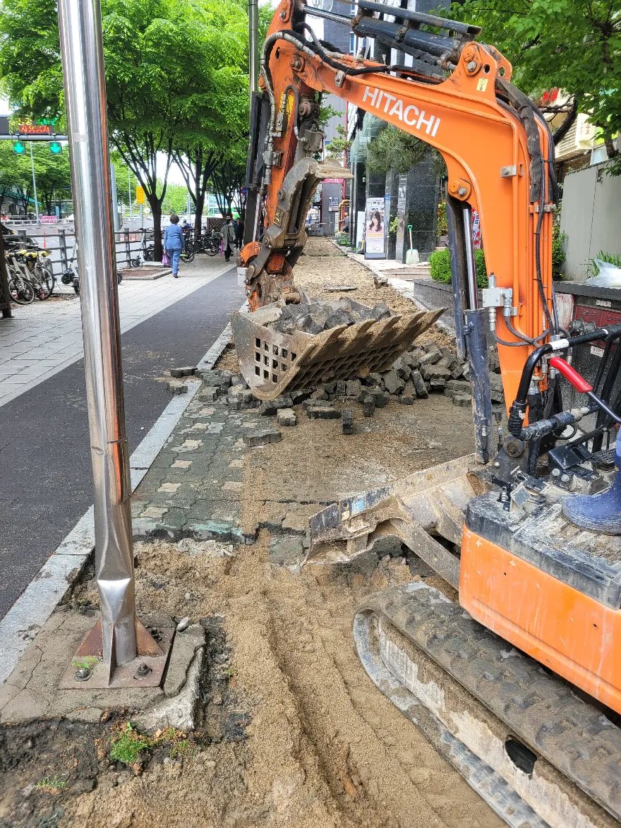소형 굴삭기로 보도블럭을 걷어내는 철거 단계입니다.