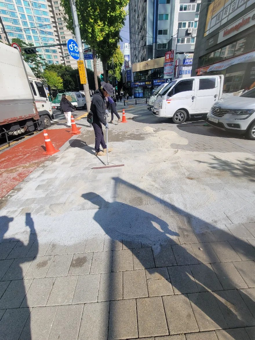 도로변 인도 보도블럭을 재시공한 뒤 줄눈 모래를 채우는 마무리 단계입니다.