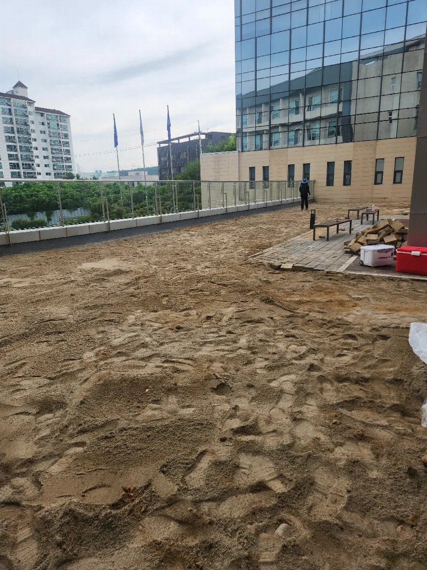 건물 옥외 테라스 공간에 보도블럭 포장을 위해 모래 기층을 포설한 상태입니다.