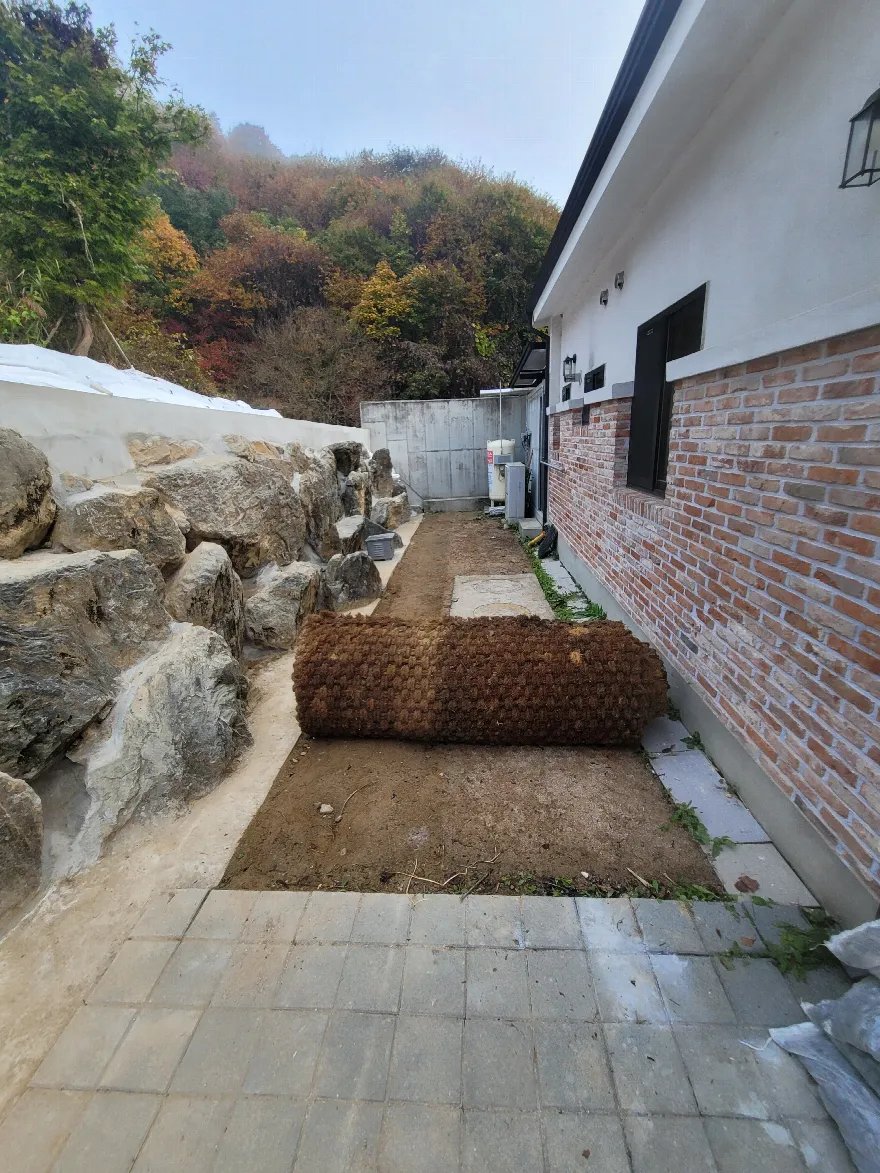 벽돌 외벽 주택과 자연석 옹벽 사이의 흙 통로에 앞으로 블럭을 깔기 위해 바닥을 정리해 둔 모습입니다.