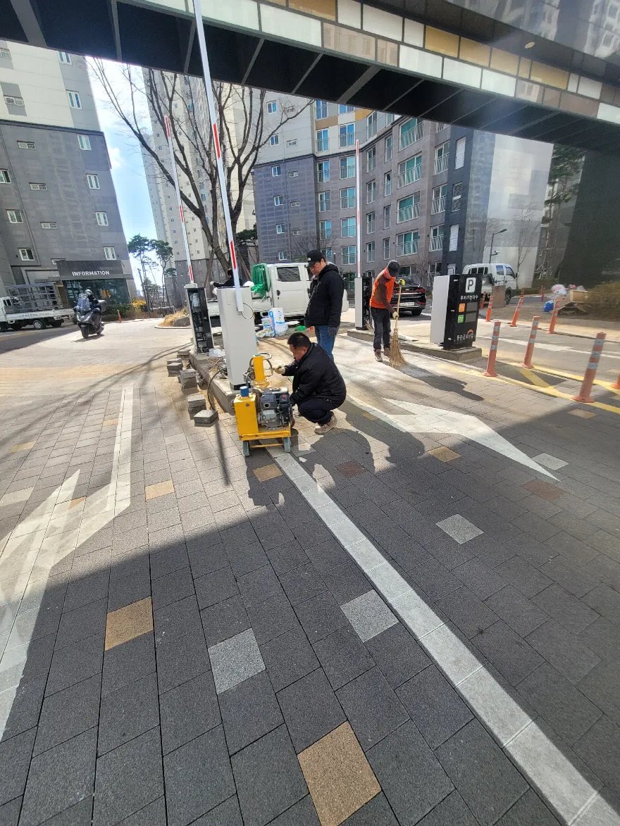 차단기와 정산기 주변 블럭을 다시 깐 뒤 노란색 플레이트 컴팩터로 다짐 작업을 하는 모습입니다.