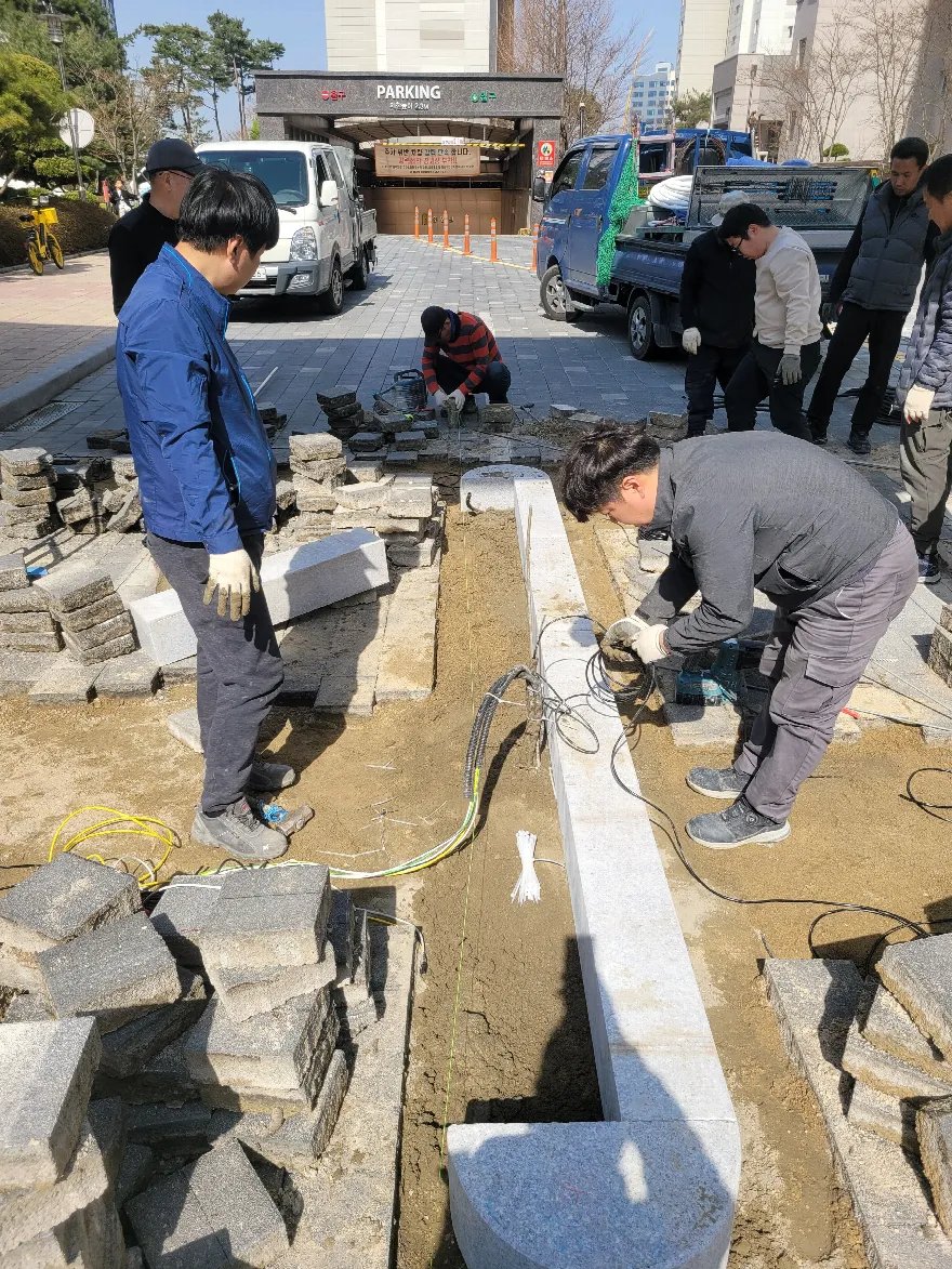 주차장 진입로 앞 구간에서 흰색 화강석 경계석을 새로 설치하는 작업입니다.
