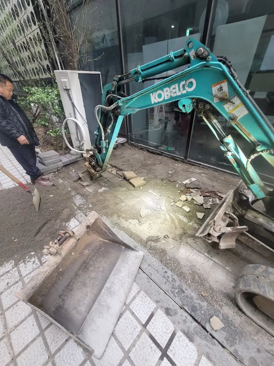소형 굴삭기로 기존 보도블럭과 기층을 걷어내는 철거 단계입니다.