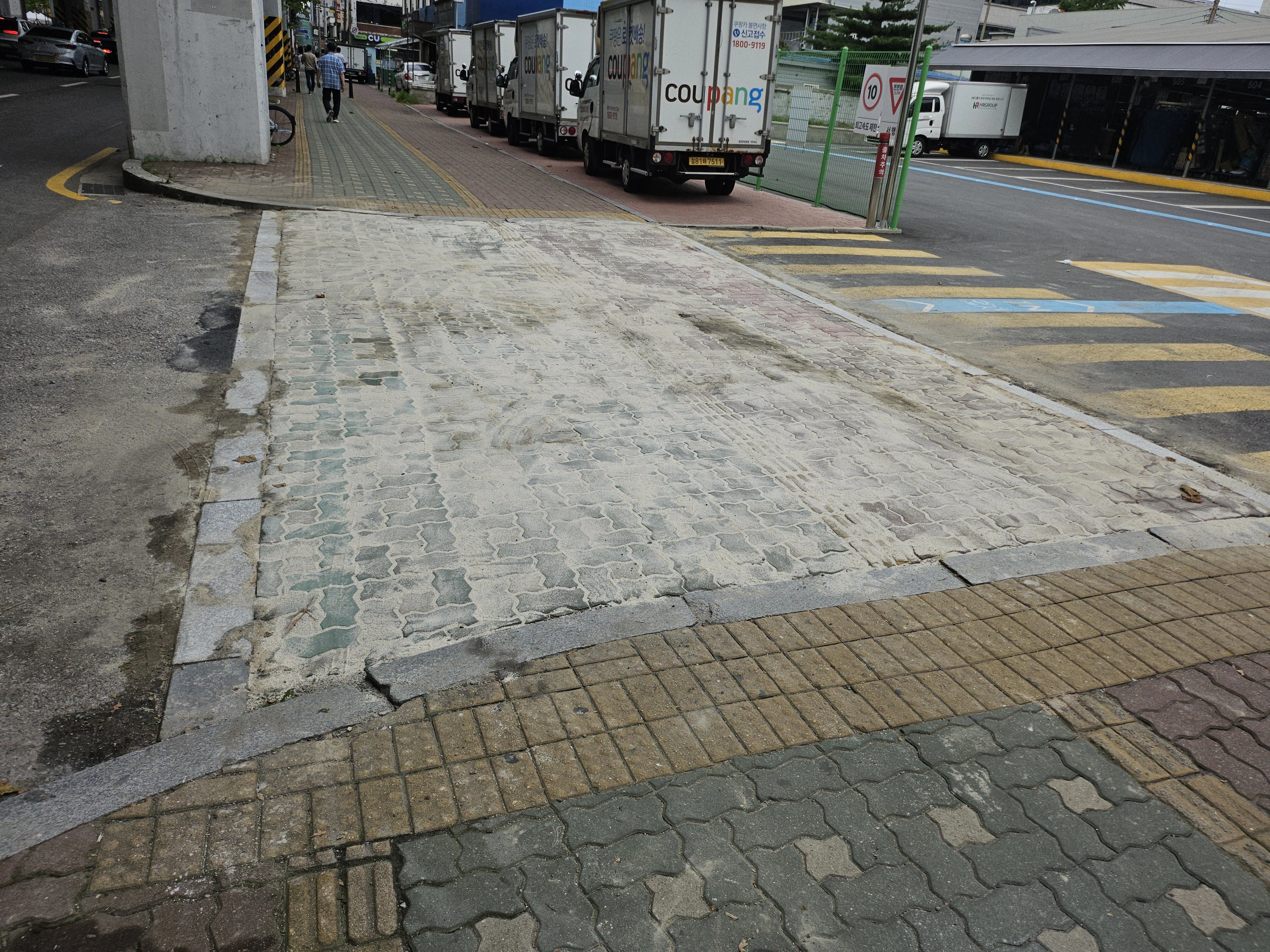 보도와 차도 경계 구간의 포장면이 벗겨지고 거칠게 패인 상태가 넓게 드러나 있습니다.