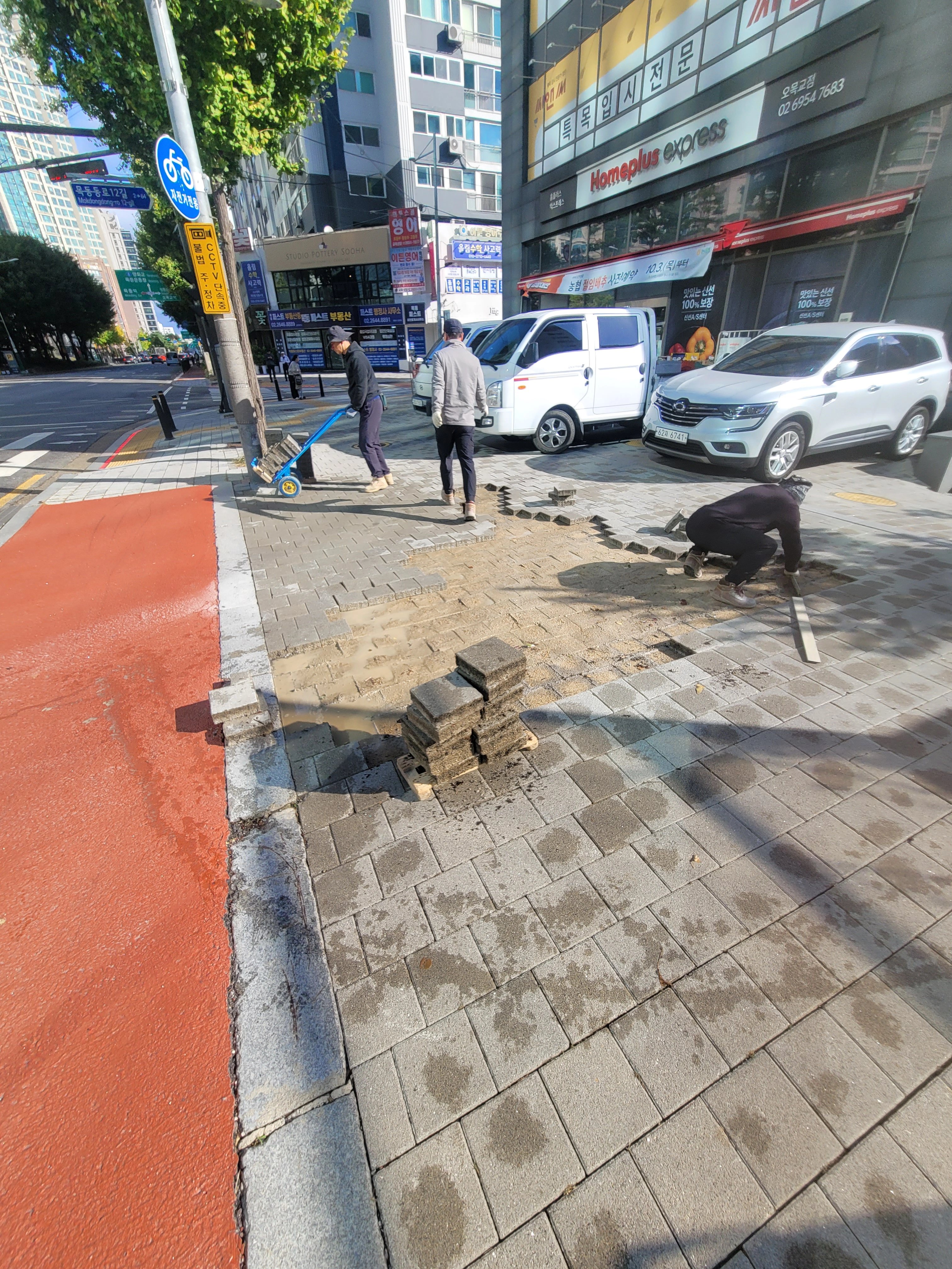 도심 인도 한편에서 보도블럭을 재시공하는 모습을 촬영한 사진입니다.