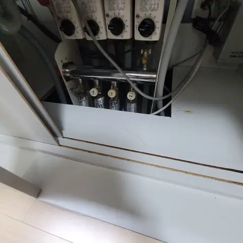 하부장 측판을 잘라 낸 안쪽에 분배기 헤더와 배관이 드러나고 하부장 하단에 오래된 오염 자국이 남은 모습