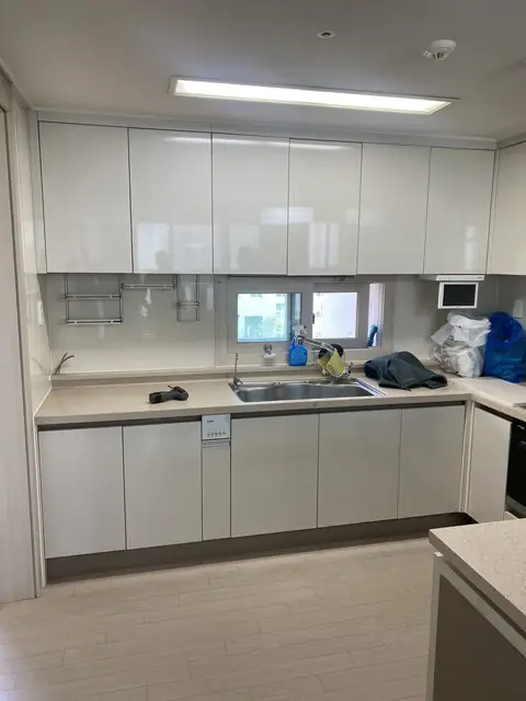흰색 광택 상부장과 손잡이 없는 하부장으로 맞춘 ㄷ자 주방