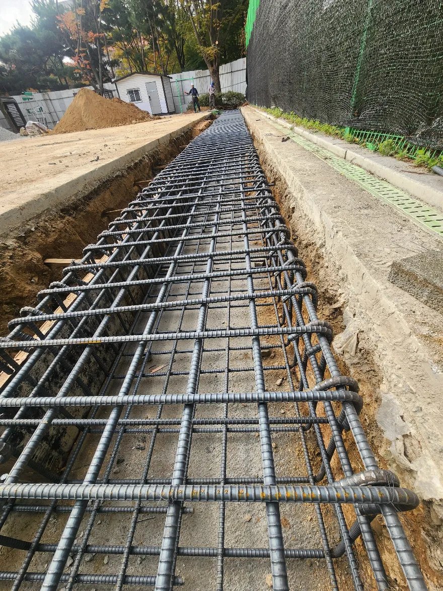 긴 트렌치 전 구간의 기초 배근이 끝난 상태를 낮은 각도에서 담은 사진입니다.