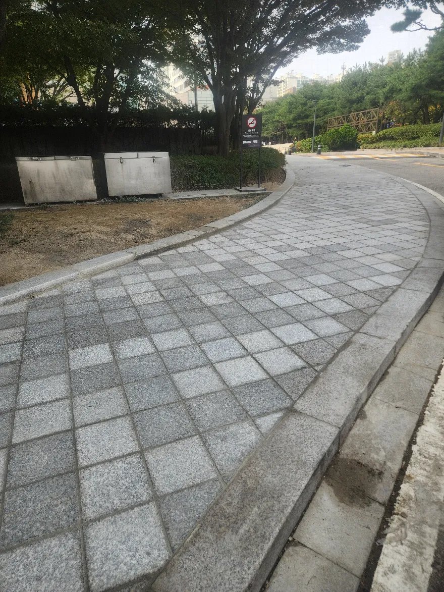 곡선으로 이어지는 보도에 두 가지 톤의 화강석 판석을 체크무늬로 배치해 시공을 마친 상태입니다.