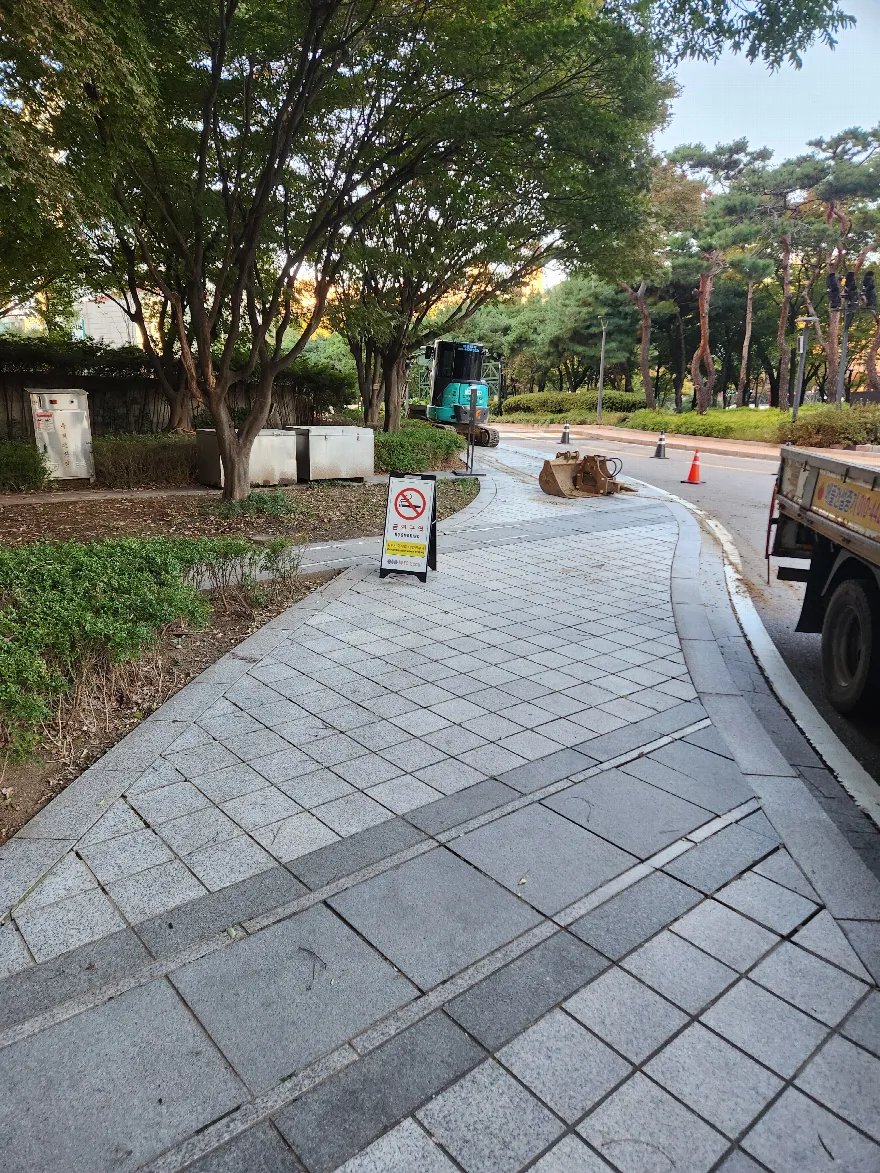 보도 판석 시공이 마무리된 구간으로, 회색 화강석 판석에 진한 색 띠 판석을 사선으로 넣어 패턴을 준 마감이 보입니다.