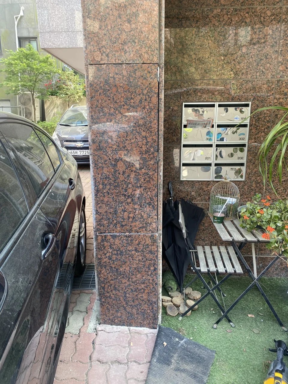 건물 출입구 기둥에 붉은빛이 도는 화강석 판석이 세로로 맞붙여 시공되어 있고, 줄눈이 가지런히 정리되어 있습니다.