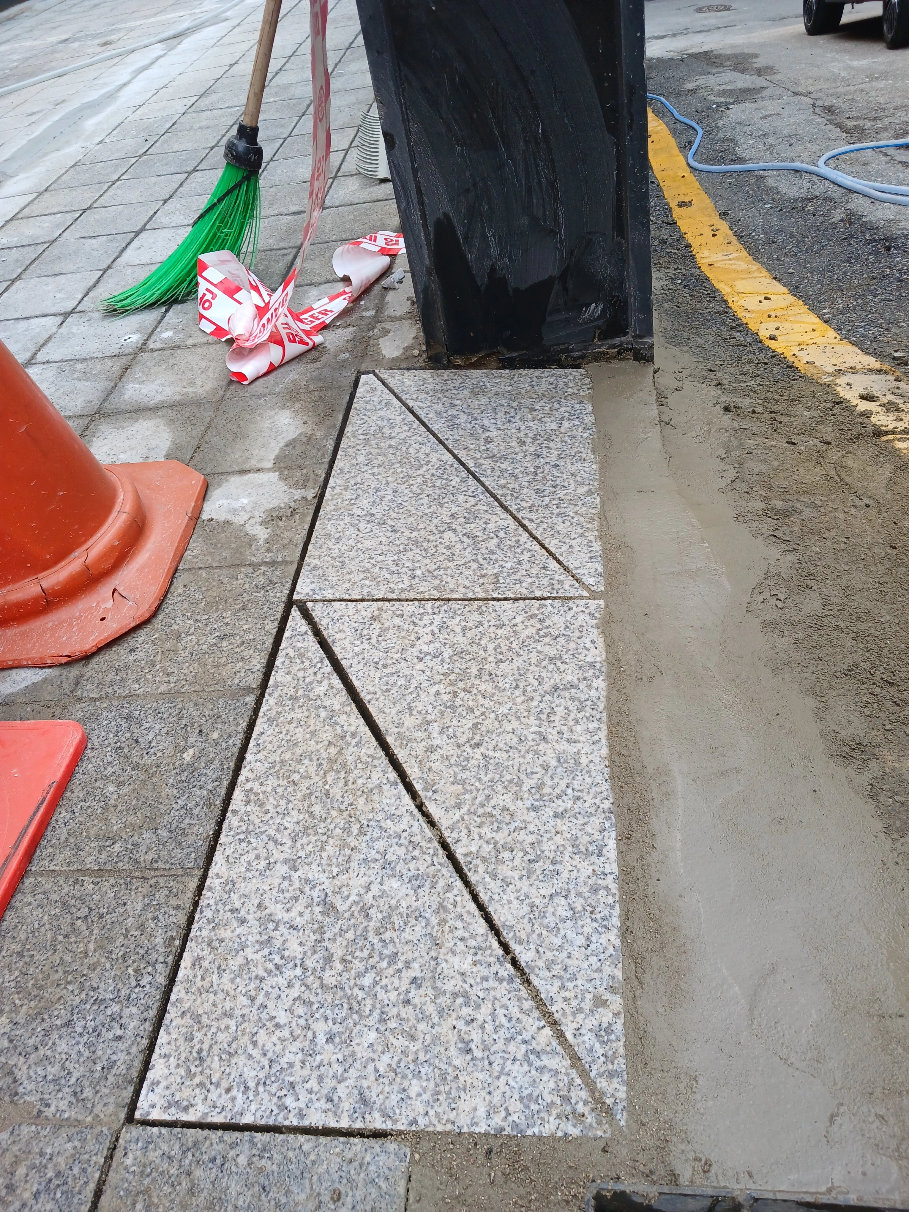 삼각형과 사다리꼴 모양으로 재단된 화강석 판석이 보도 일부 구간에 맞춰 깔린 모습입니다.