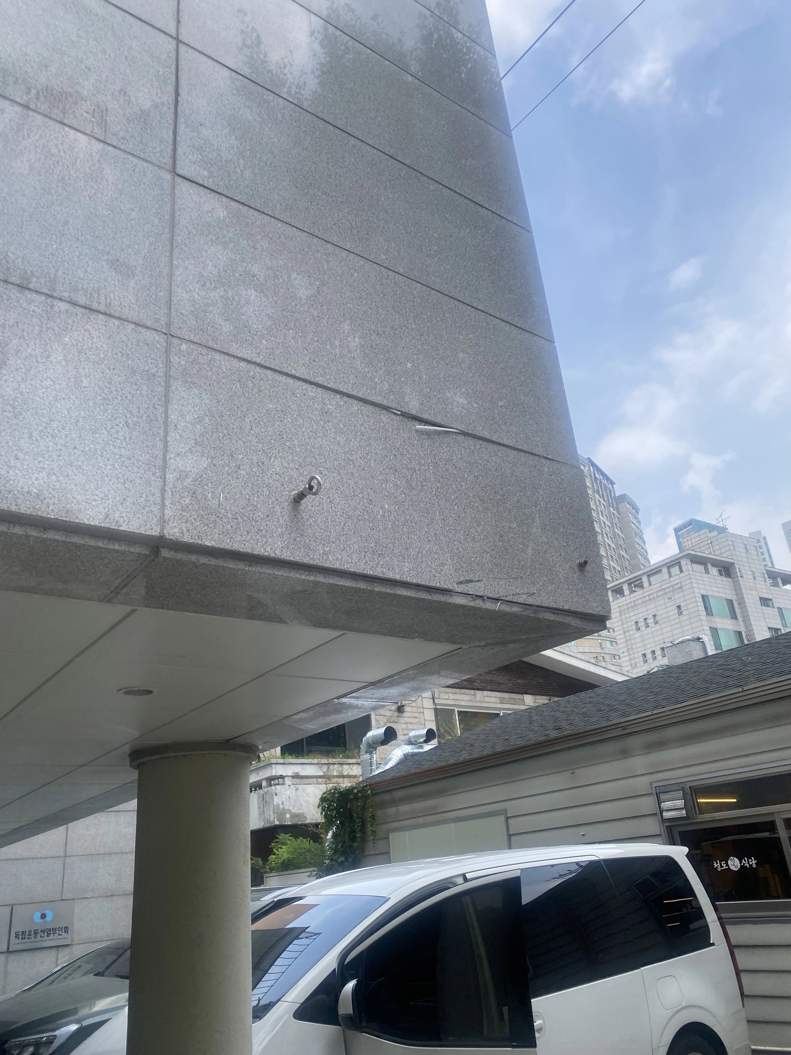건물 모서리 외벽에 시공된 화강석 계열 판석의 전체 모습을 아래에서 올려다본 사진입니다.