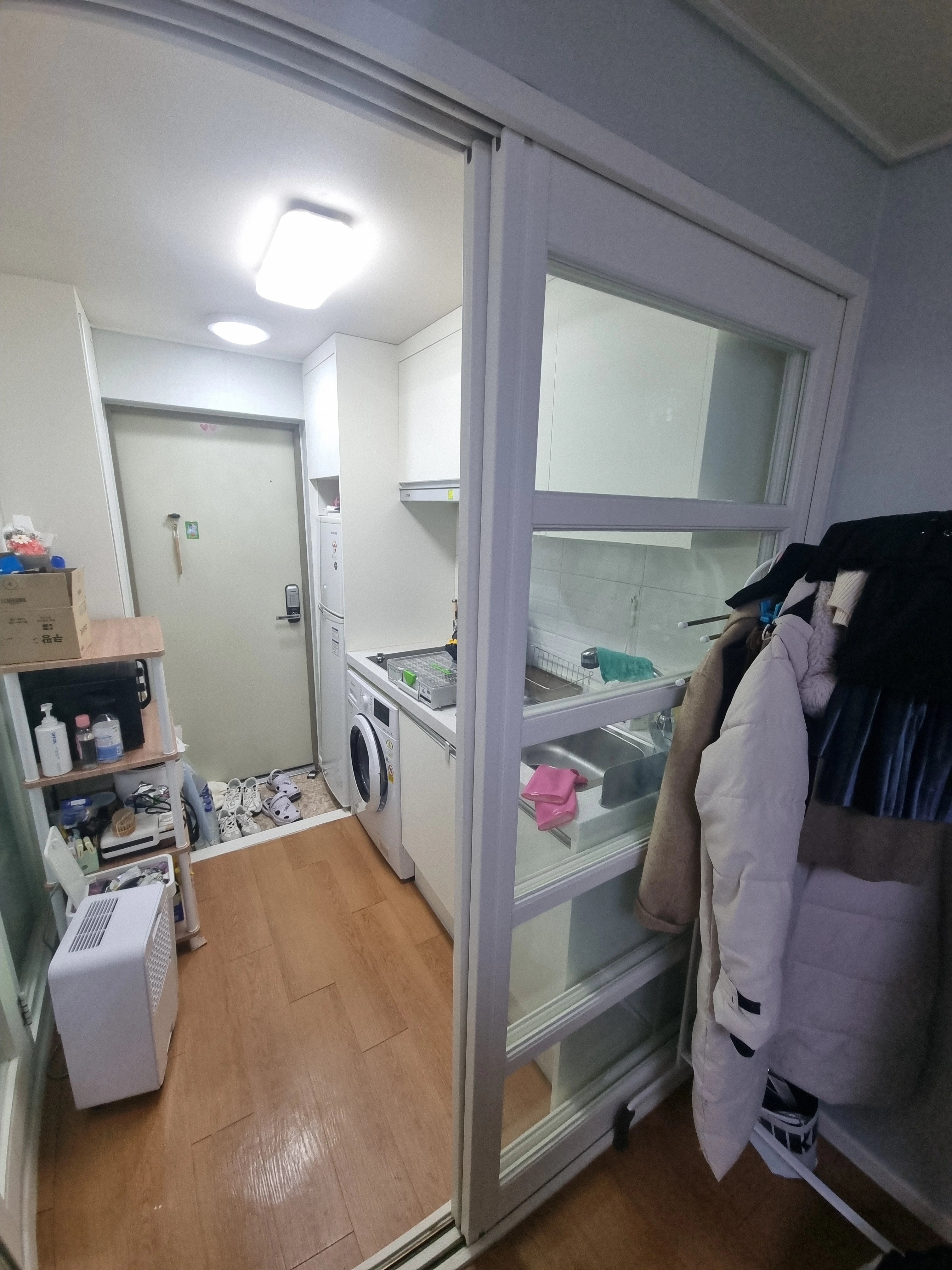 다용도실로 보이는 공간에 흰색 프레임의 미닫이 창호(도어)가 새로 설치되어 있는 모습입니다.