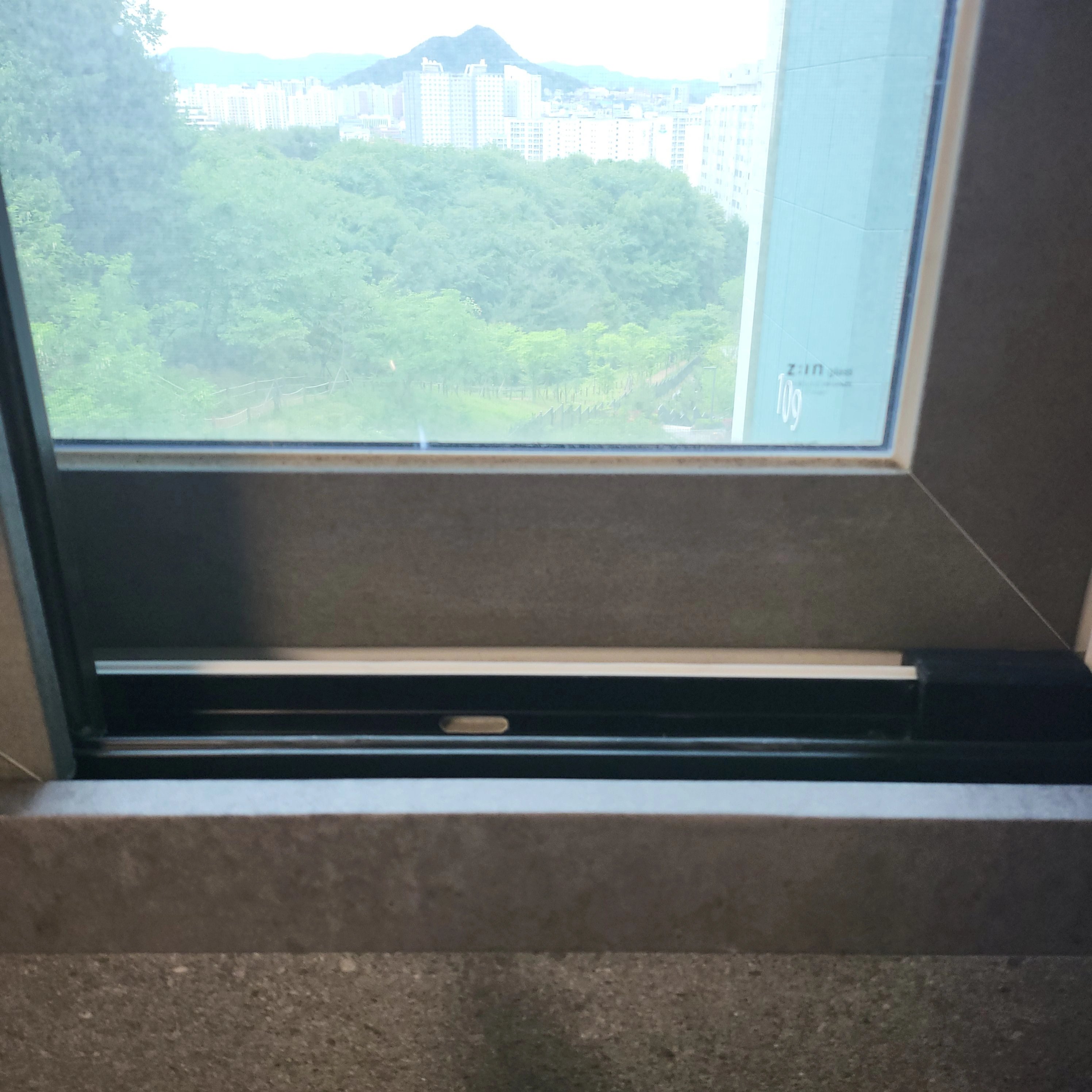 창문 하단 샷시 레일과 손잡이 부분을 가까이에서 찍은 사진입니다.