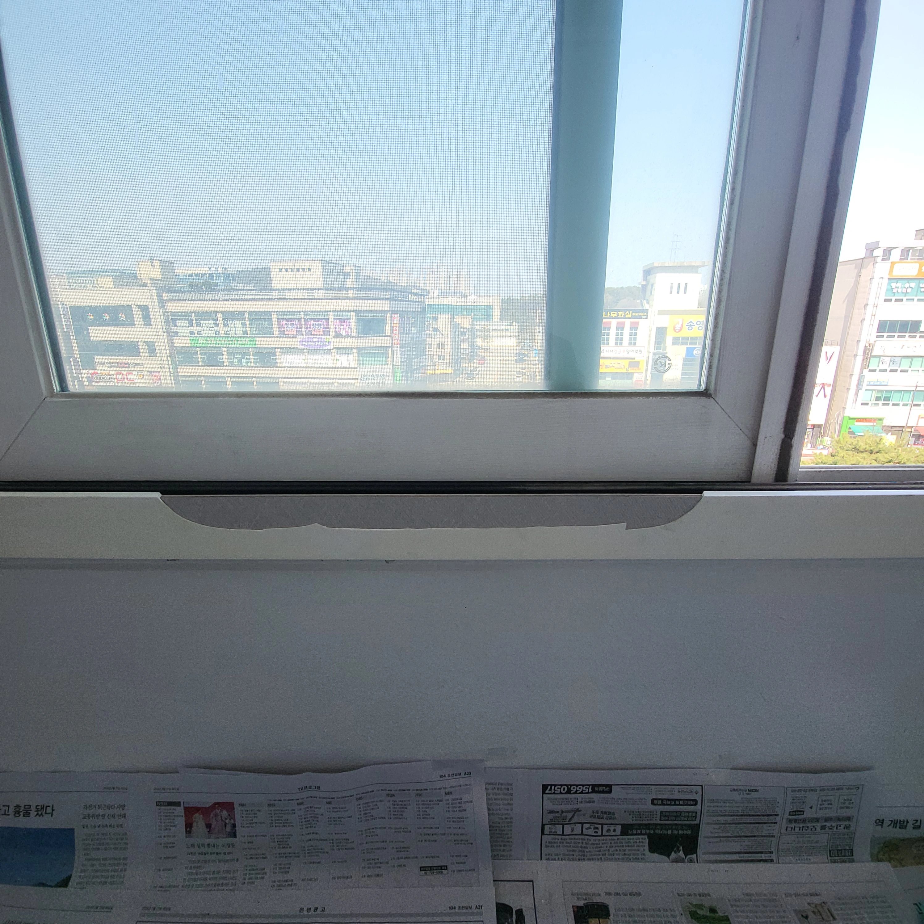 흰색 PVC 창틀에 새시가 끼워진 상태로, 하부 레일 쪽에 실리콘으로 보이는 마감선이 길게 발라져 있습니다.