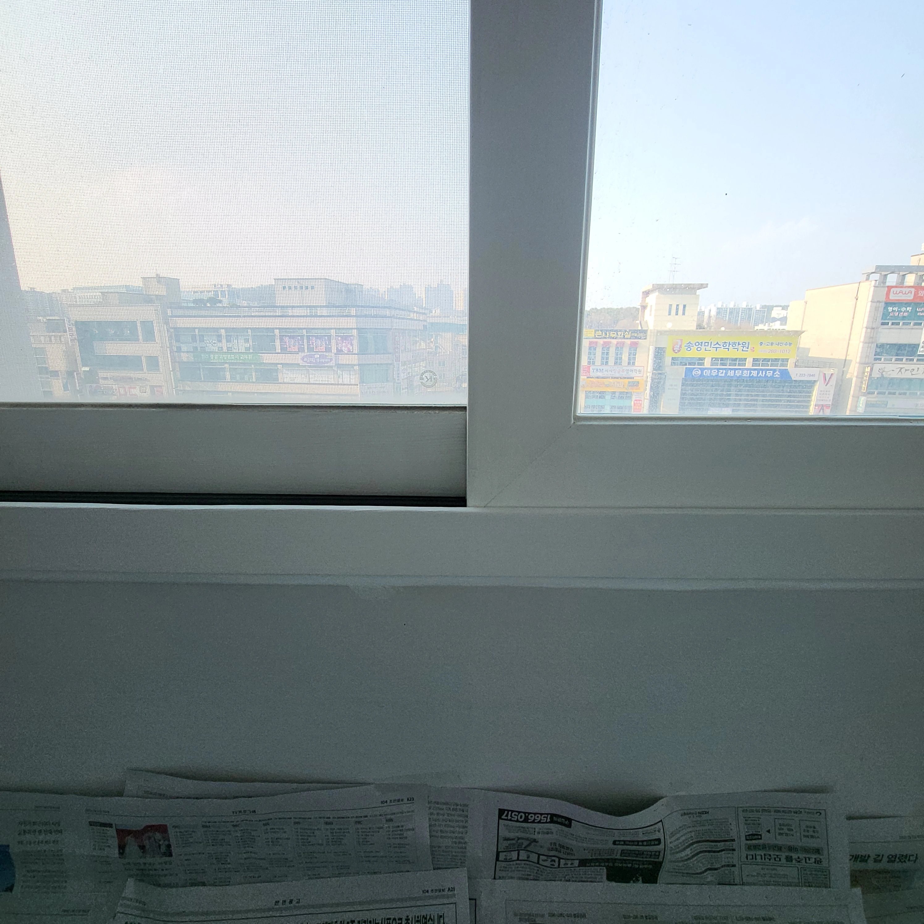 실내에서 바라본 이중 미서기창으로 창밖으로 주변 건물들이 보임.